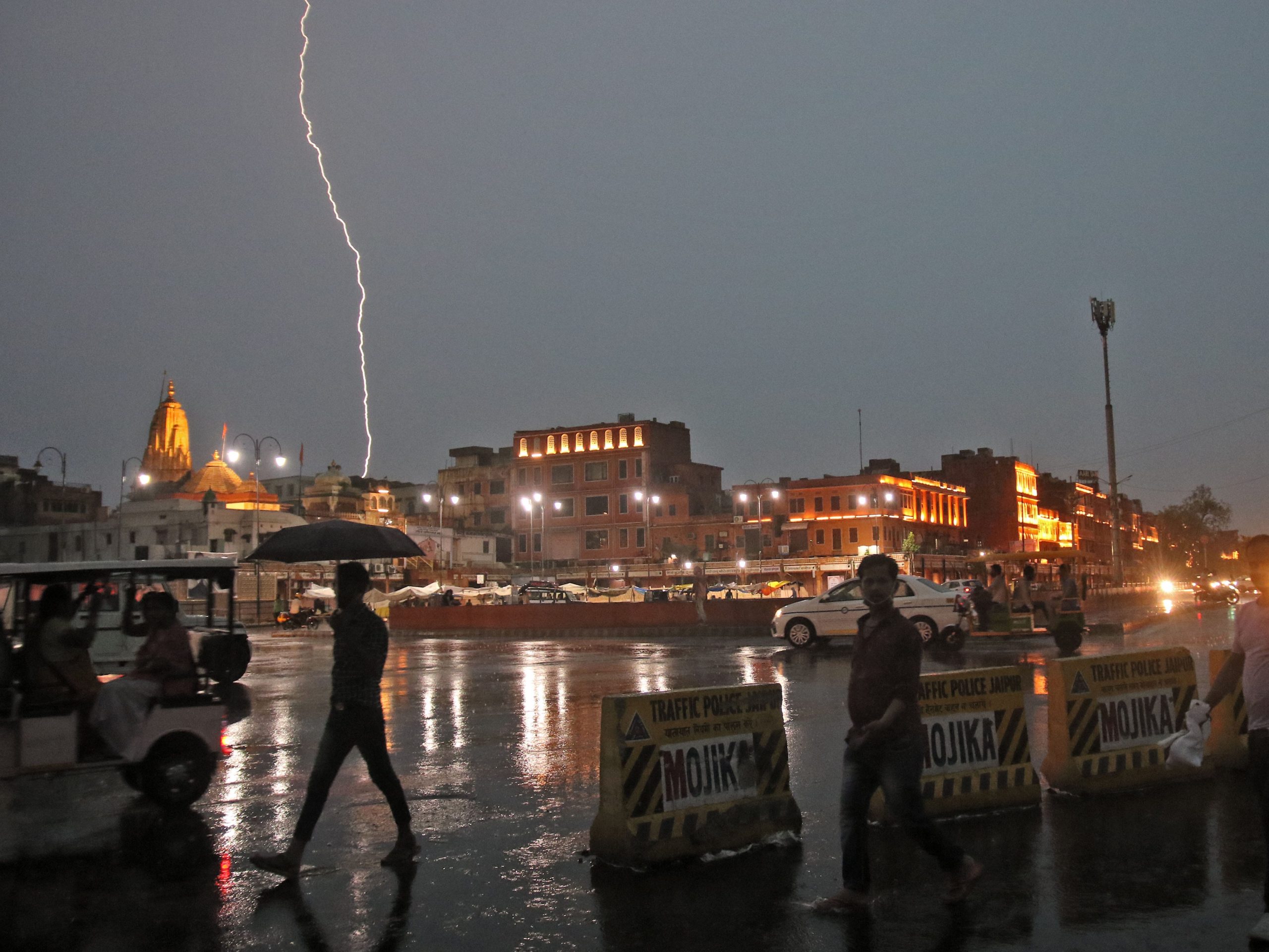 Commuters crosses a road as it rains during a lightning strike in the sky in Jaipur, Rajasthan, India, July 11, 2021.