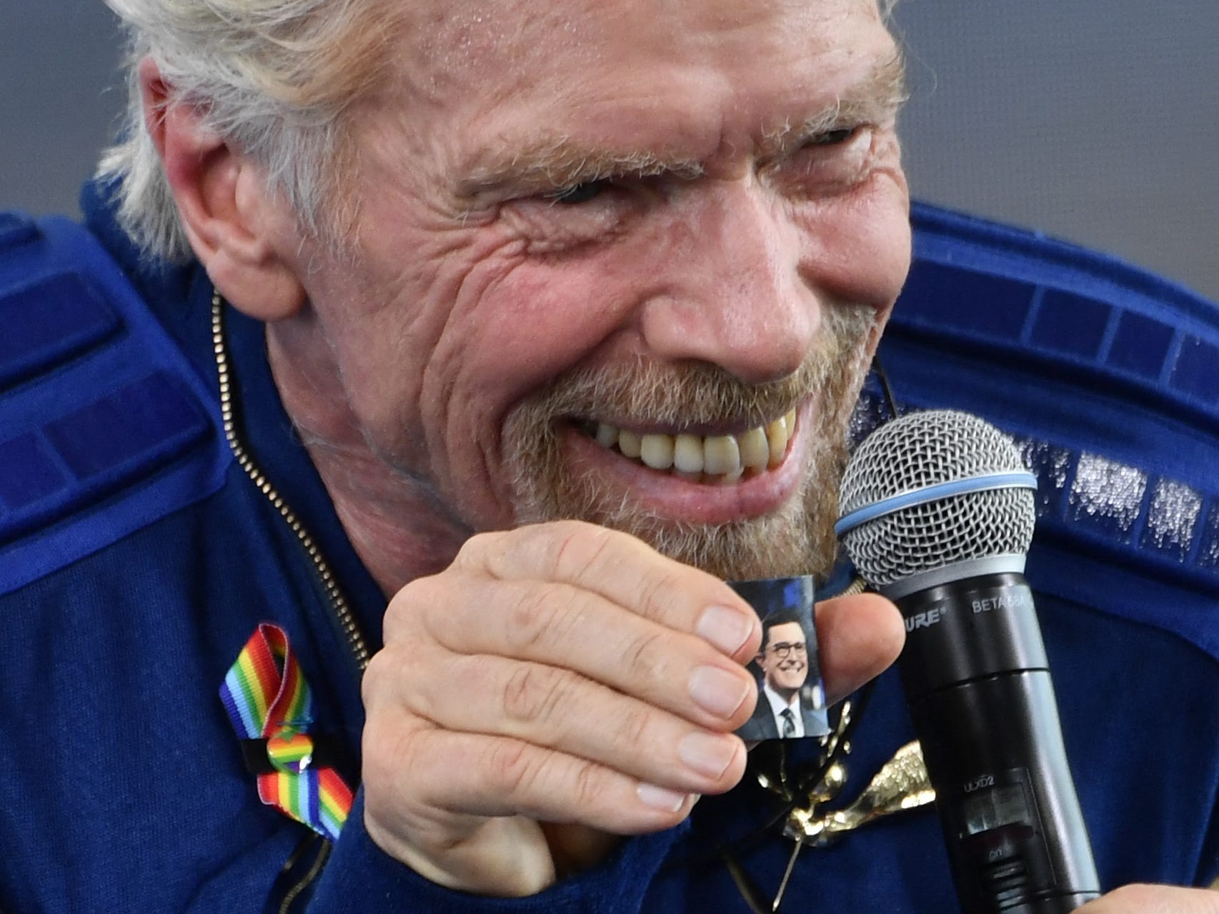 richard branson holds photo of stephen colbert