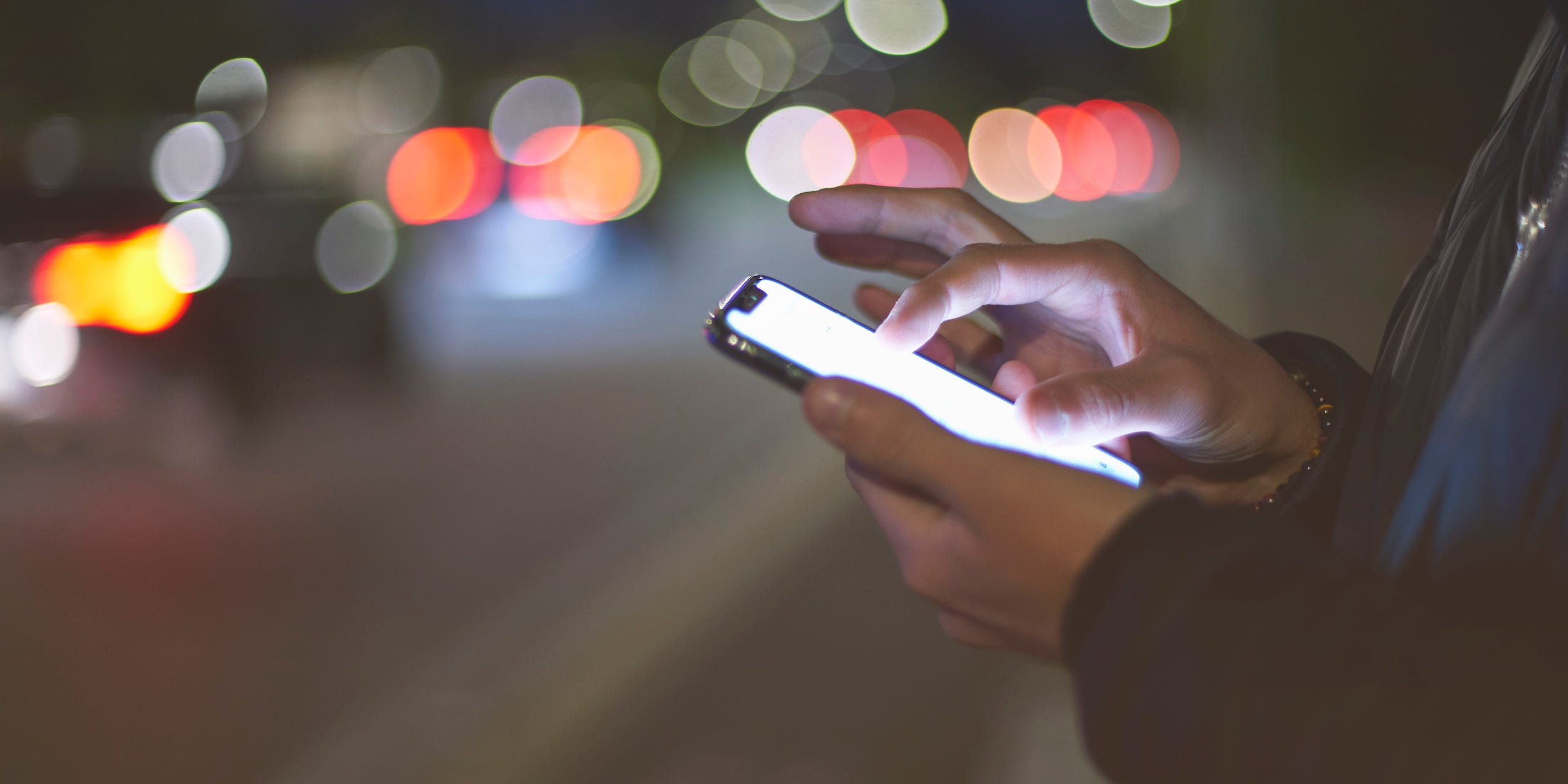 person using bright phone outside at night