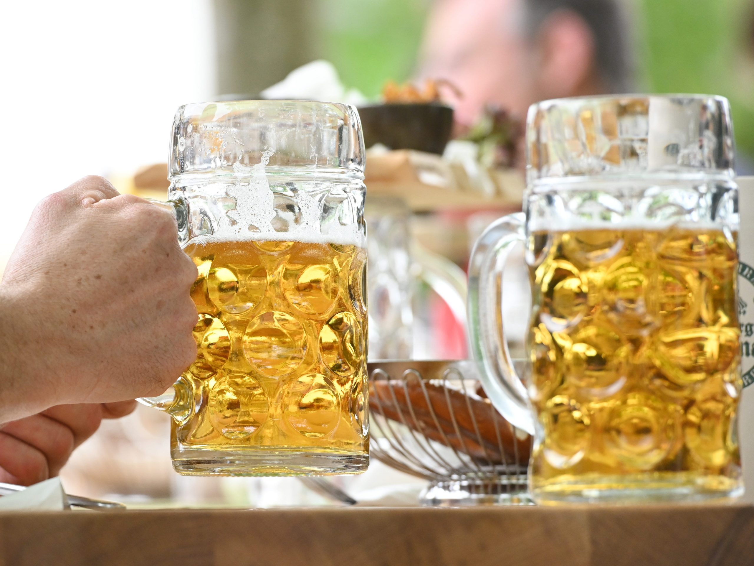 A guest reaches for a beer mug in the beer garden at the "Gasthof zur Brücke"