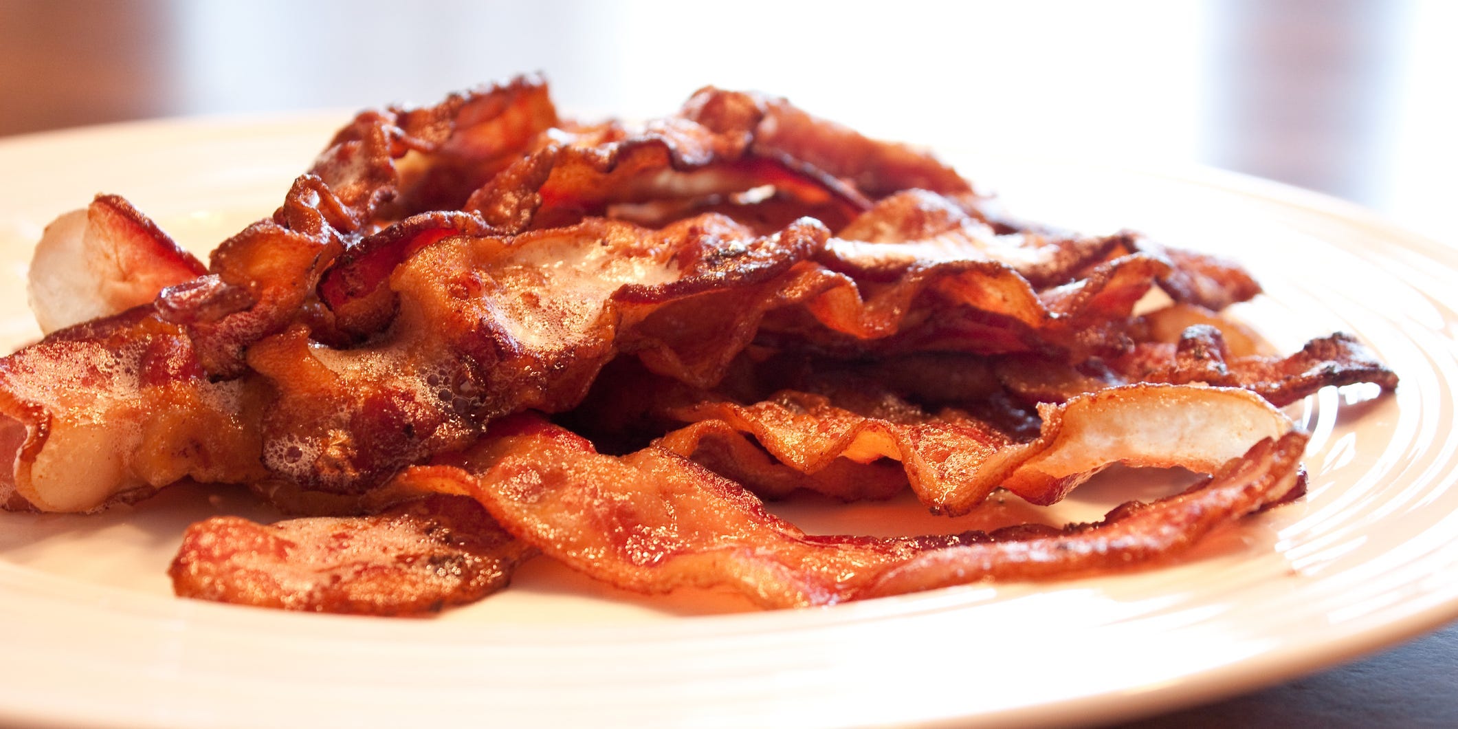 A pile of crispy bacon on a white plate