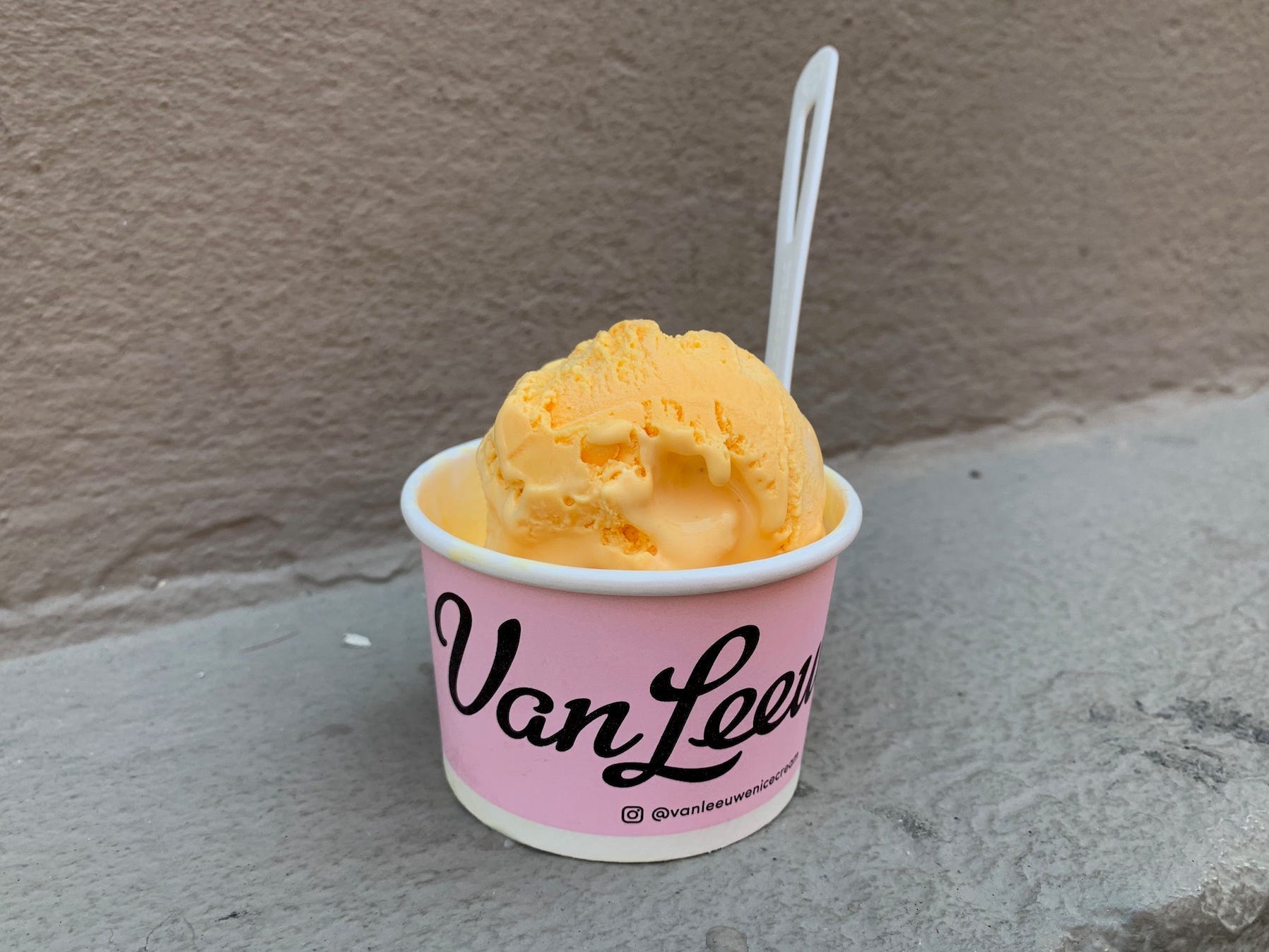 A pink cup filled with yellow ice cream.