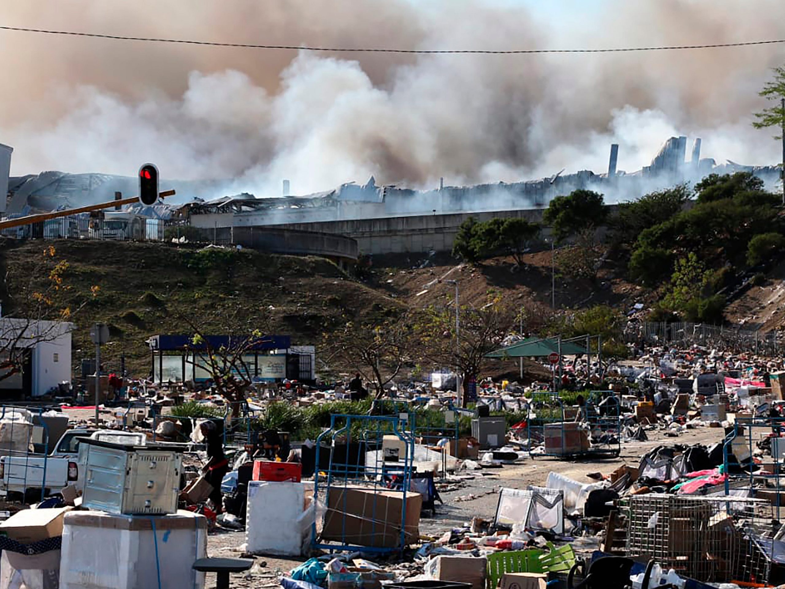 A factory burns in the background while empty boxes litter the foreground from looted goods being removed, on the outskirts of Durban, South Africa.