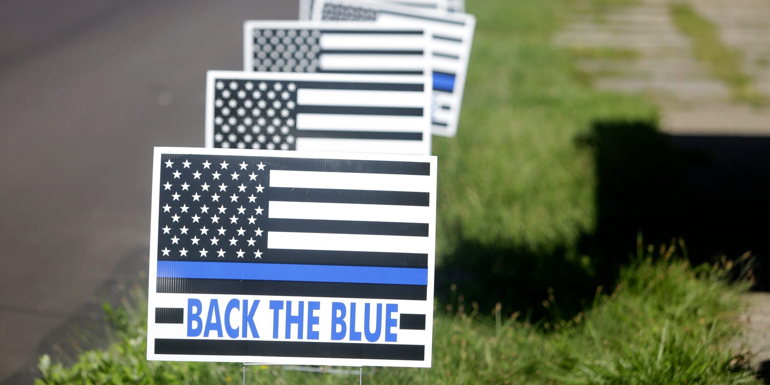 BACK THE BLUE signs line a road.