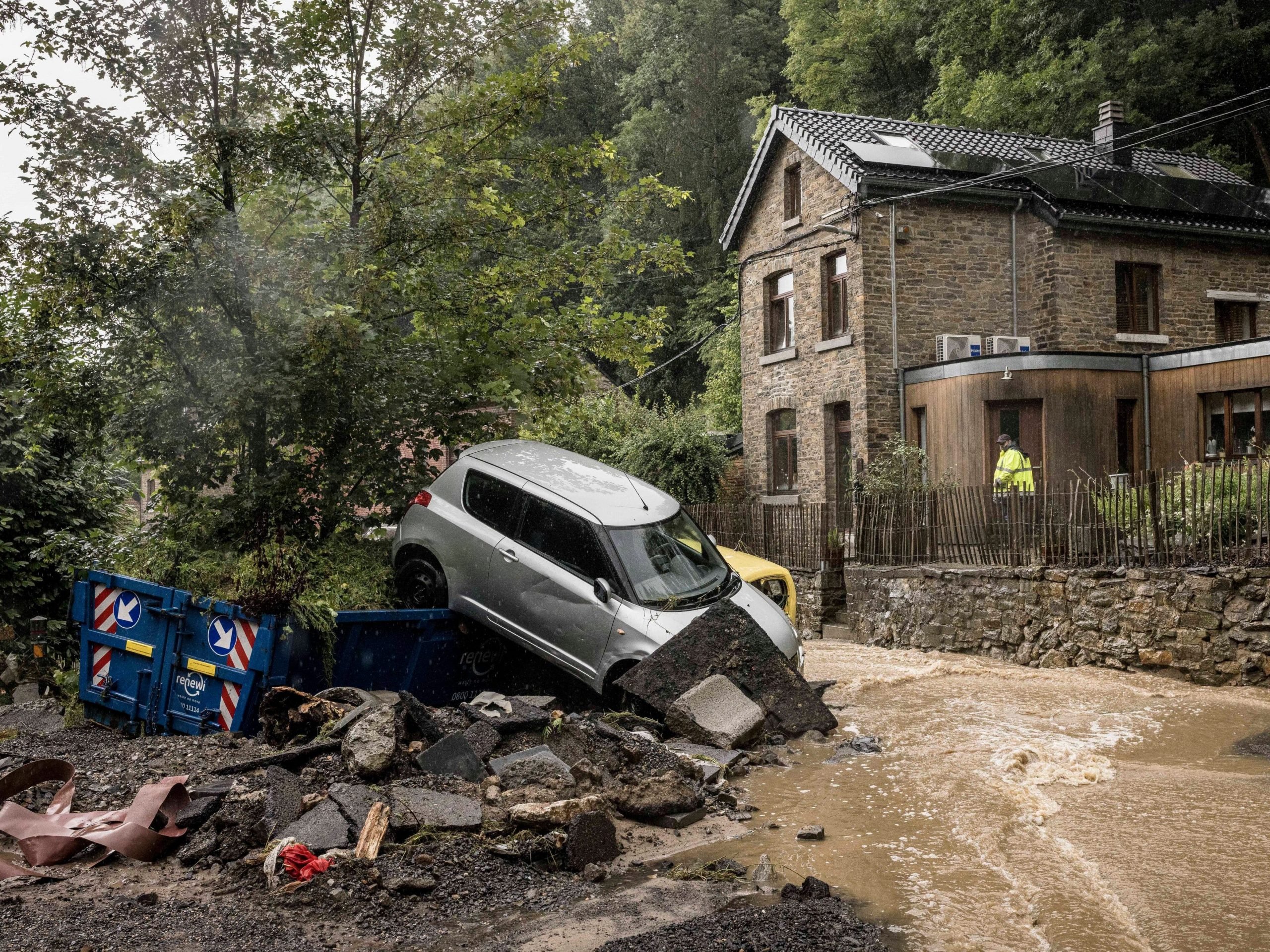 A man looks at damaged cars in a flooded street in Mery, Province of Liege, Belgium, July 14, 2021. A code red was issued in parts of Belgium on Wednesday as severe rains hit the area.