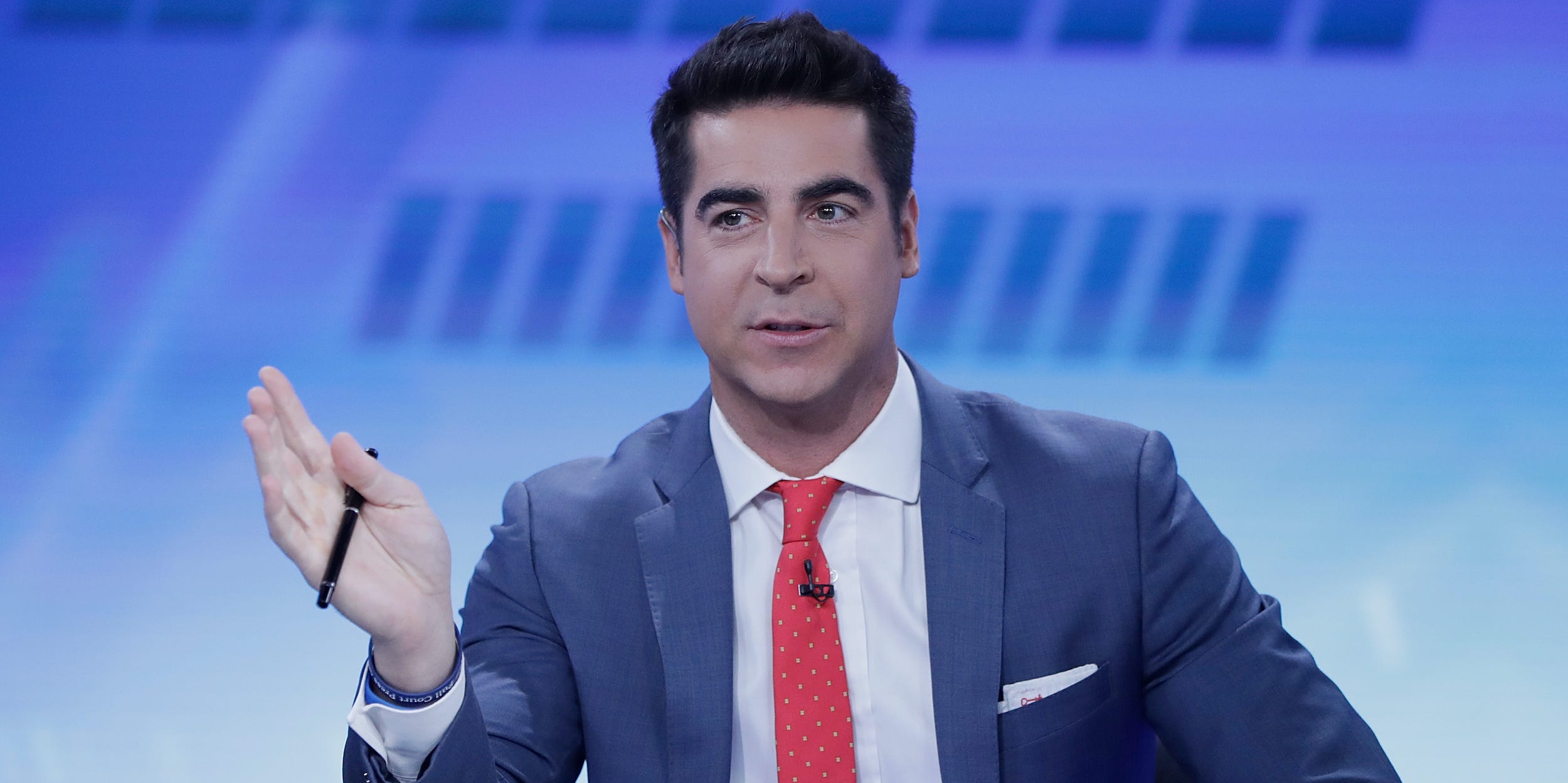 Fox News host Jesse Watters gestures with a pen in his right hand.