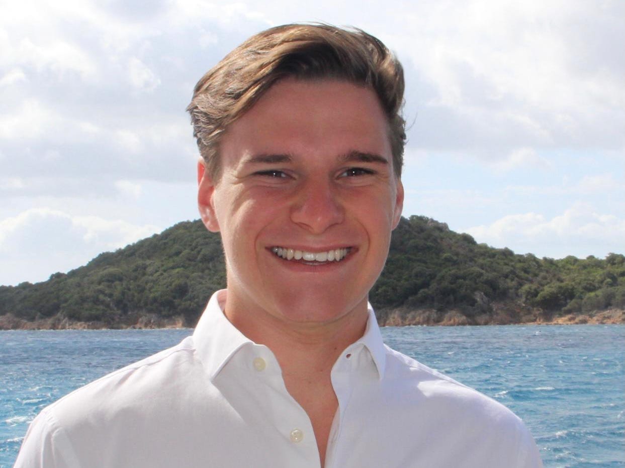 Oliver Daeman smiling in front of water and mountain