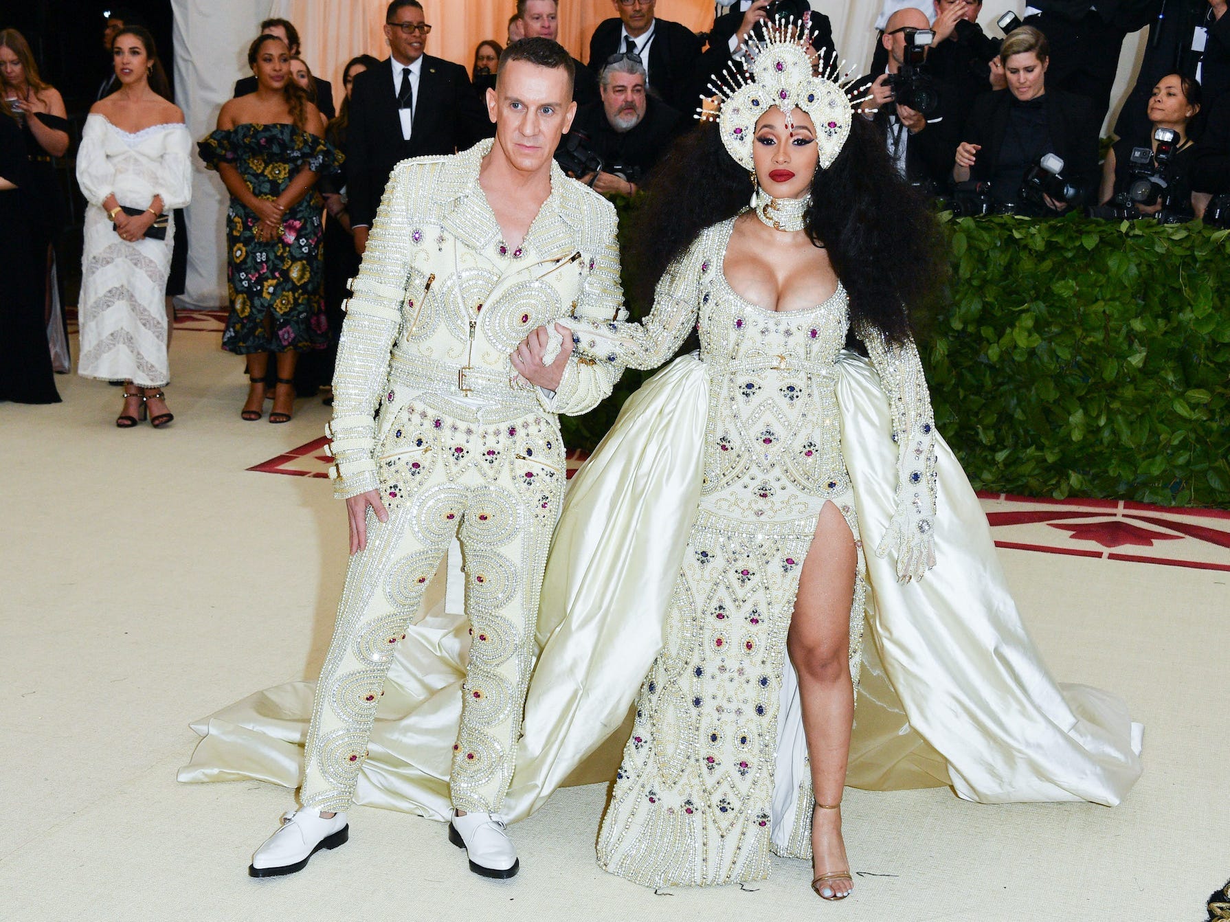 Jeremy Scott and Cardi B stand in cream, bedazzled outfits on the Met Gala carpet.