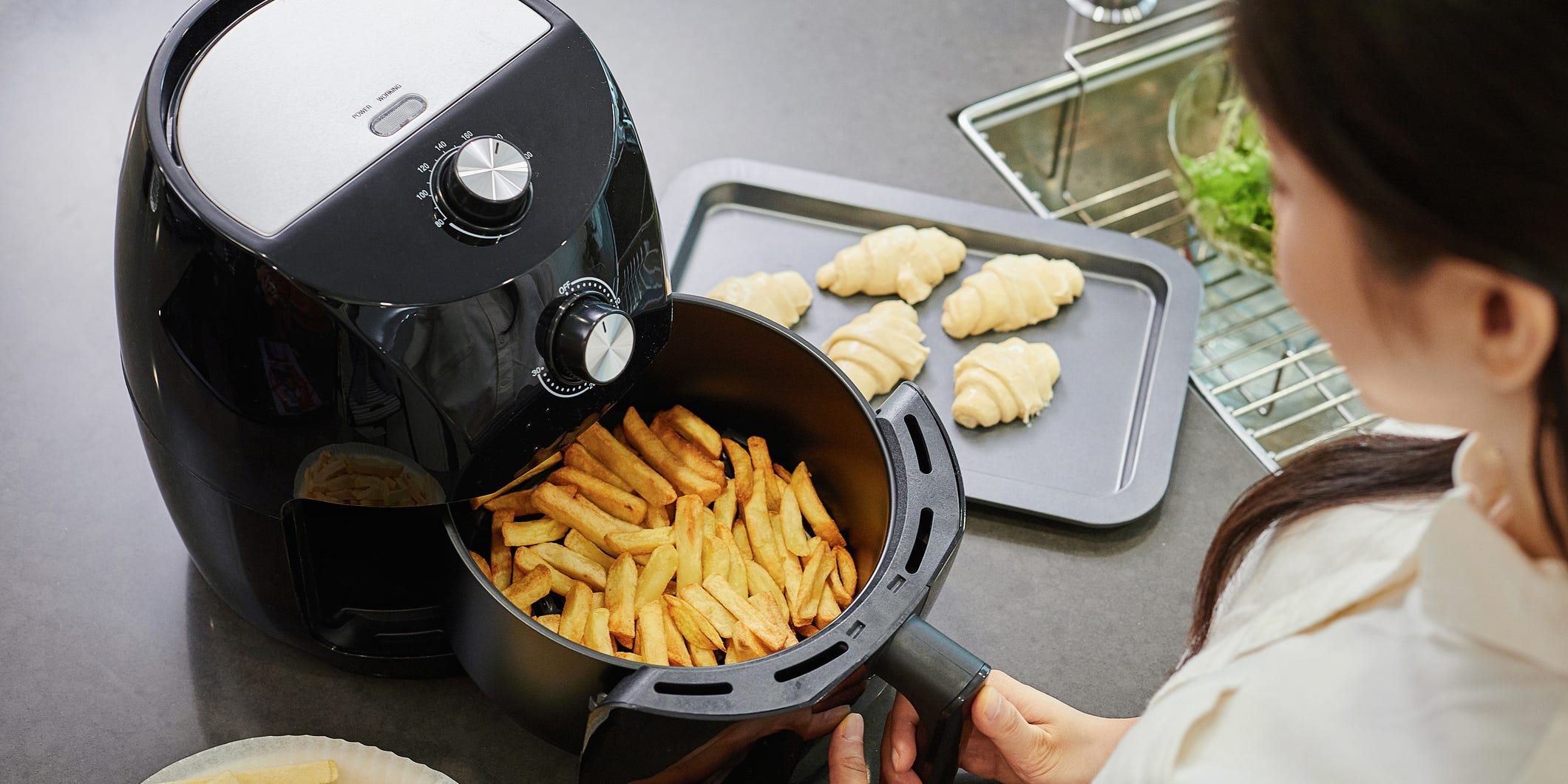 A person starting a batch of french fries in an air fryer