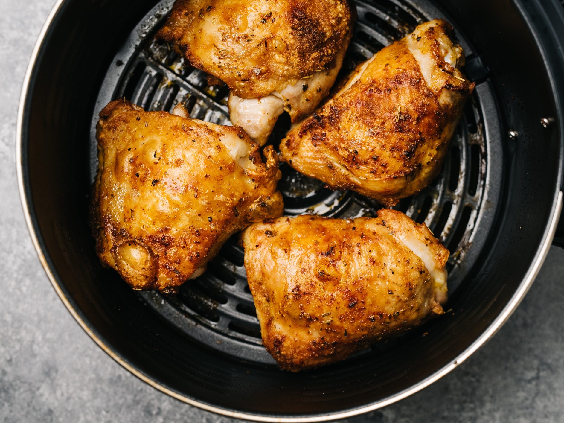 Four chicken thighs in the basket of an air fryer