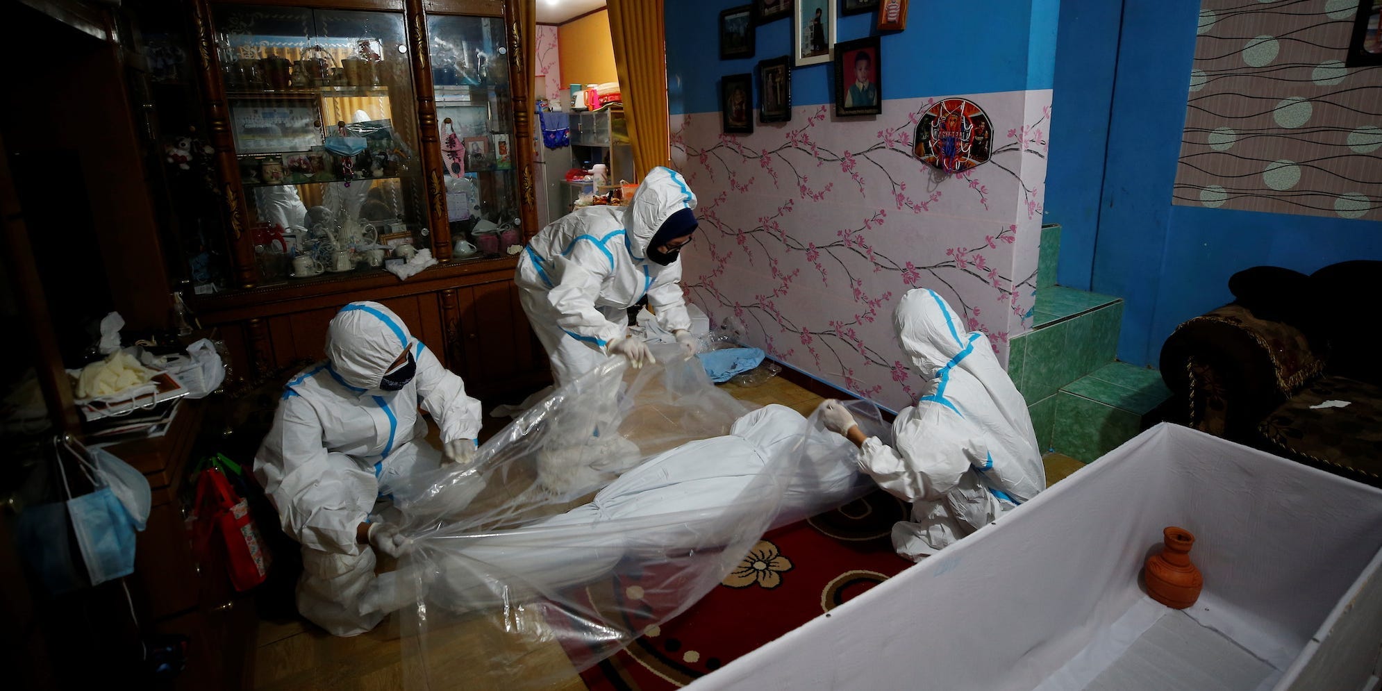 People in PPE cover a body in a home