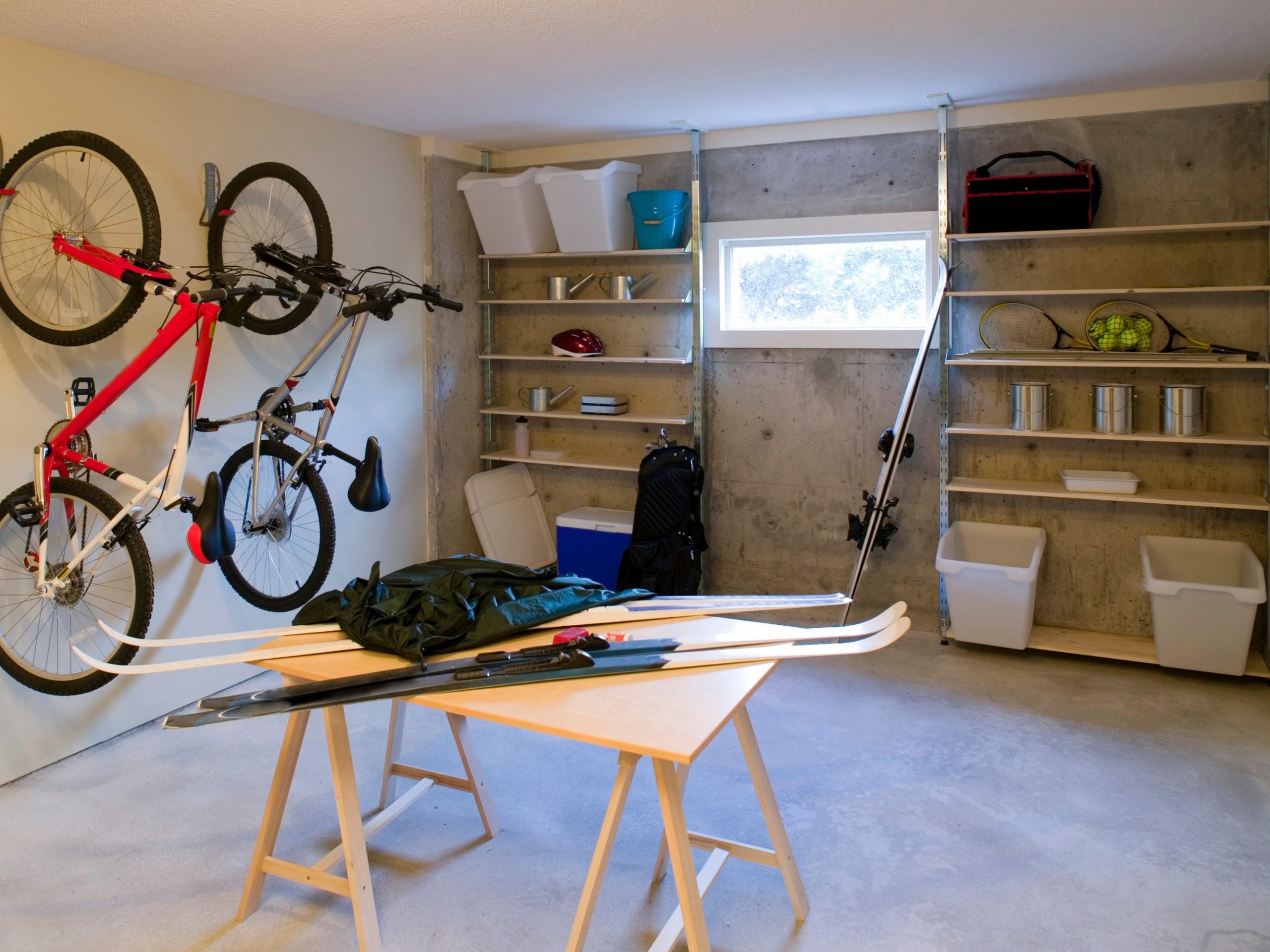 Interior of a garage with shelving, bikes mounted on the wall, and a table in the middle.