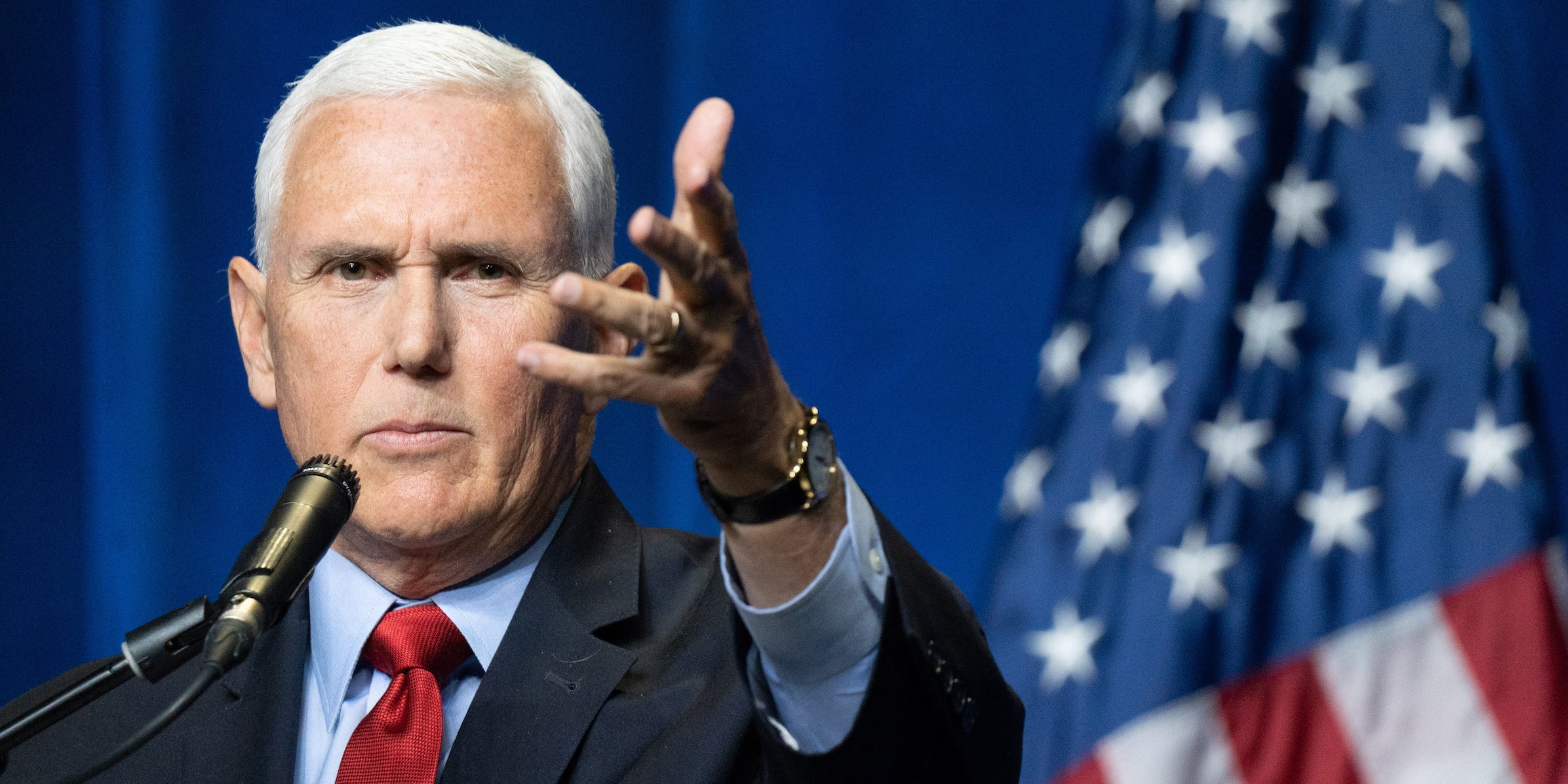 Former Vice President Mike Pence gestures forward with his open left hand tilted sideways.