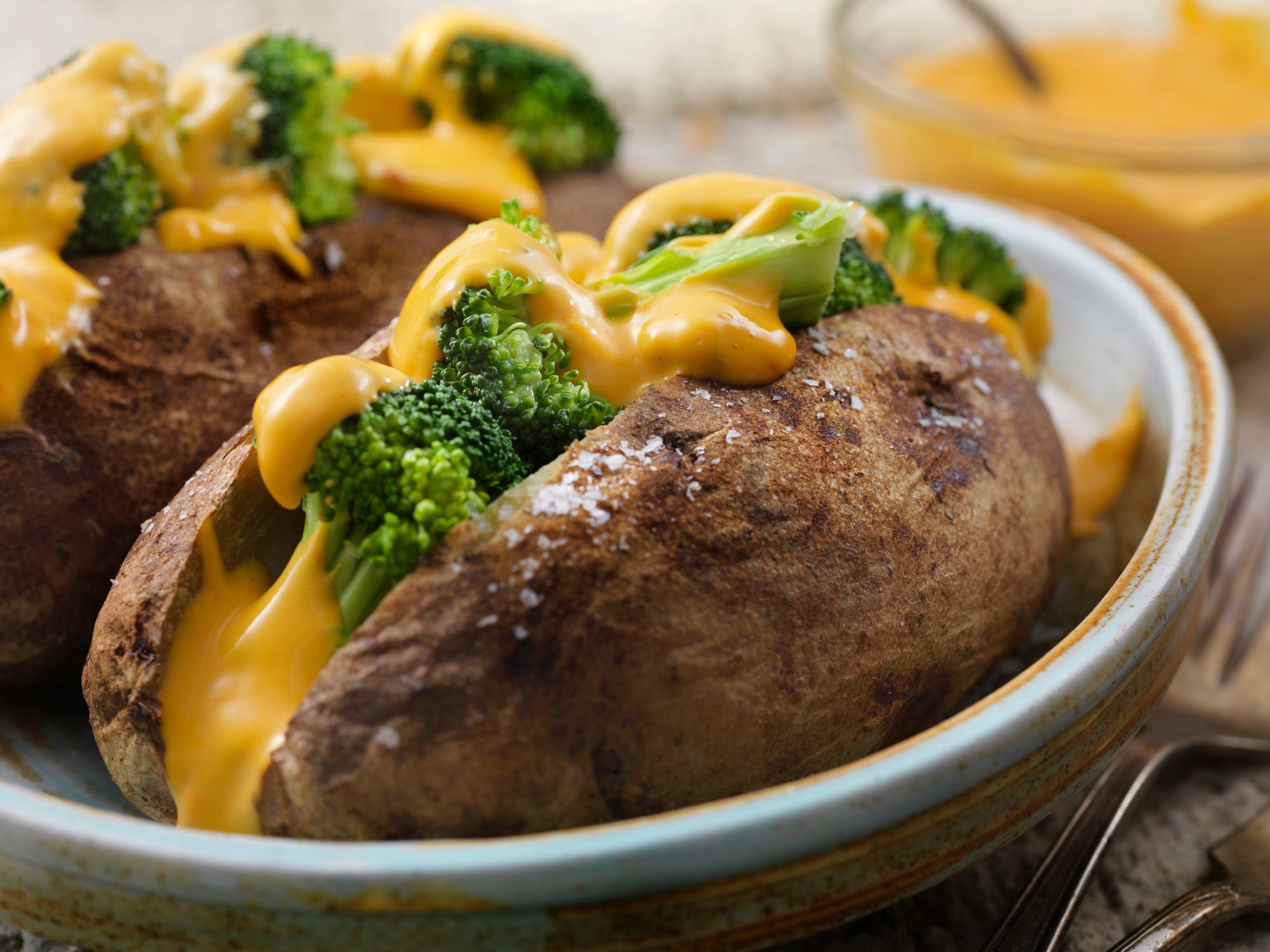 A baked potato sliced open and stuffed with broccoli and cheese sauce