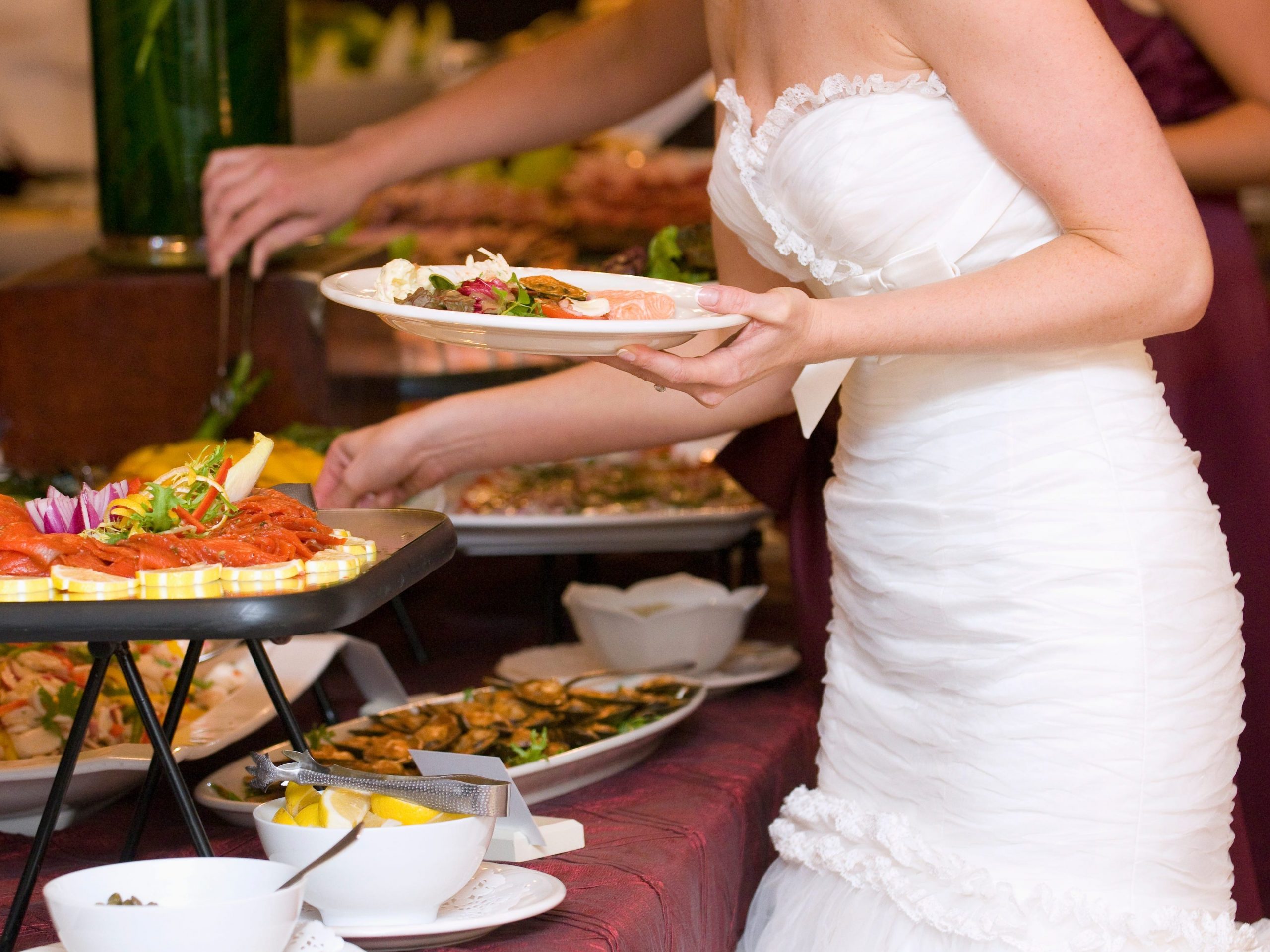 A bride chooses food during her wedding reception.