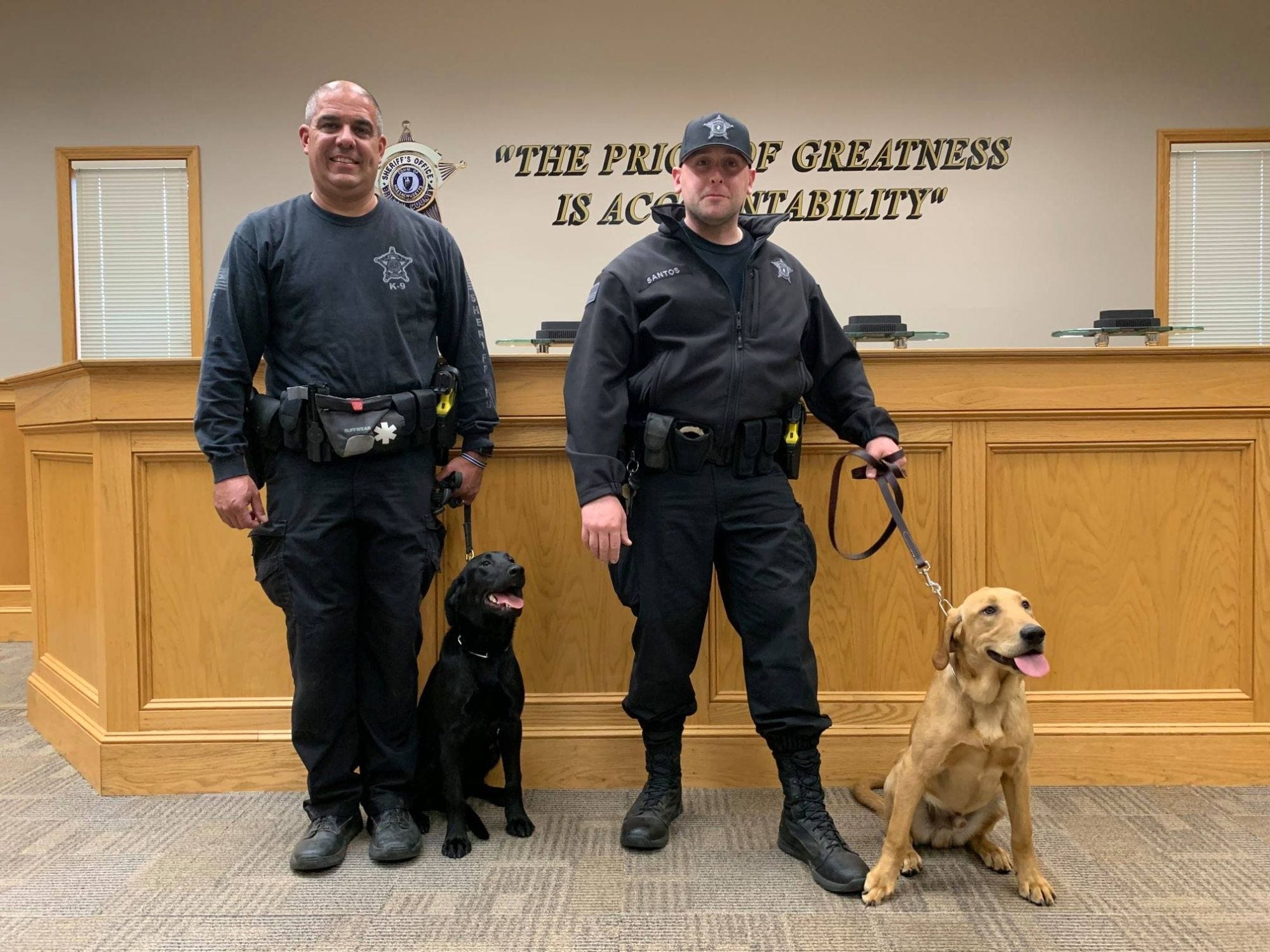 Two officers from the Bristol County Sheriff’s Office pose with their two canine partners.