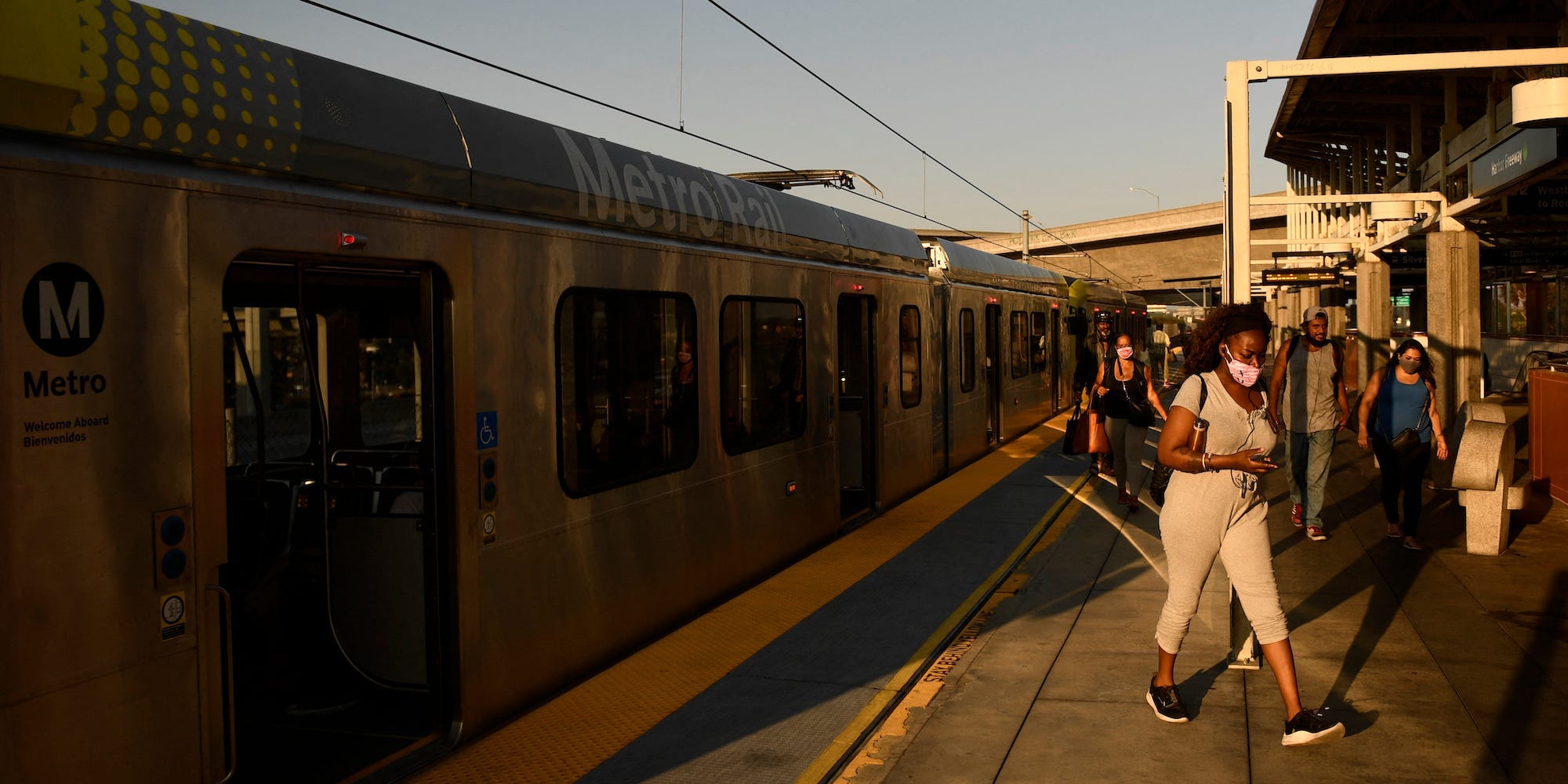 Transit passengers wear face masks as they disembark the Metro C Line, formerly Green Line, light rail train alongside the 105 Freeway at the Judge Harry Pregerson Interchange during rush hour traffic in Los Angeles, California on July 16, 2021.