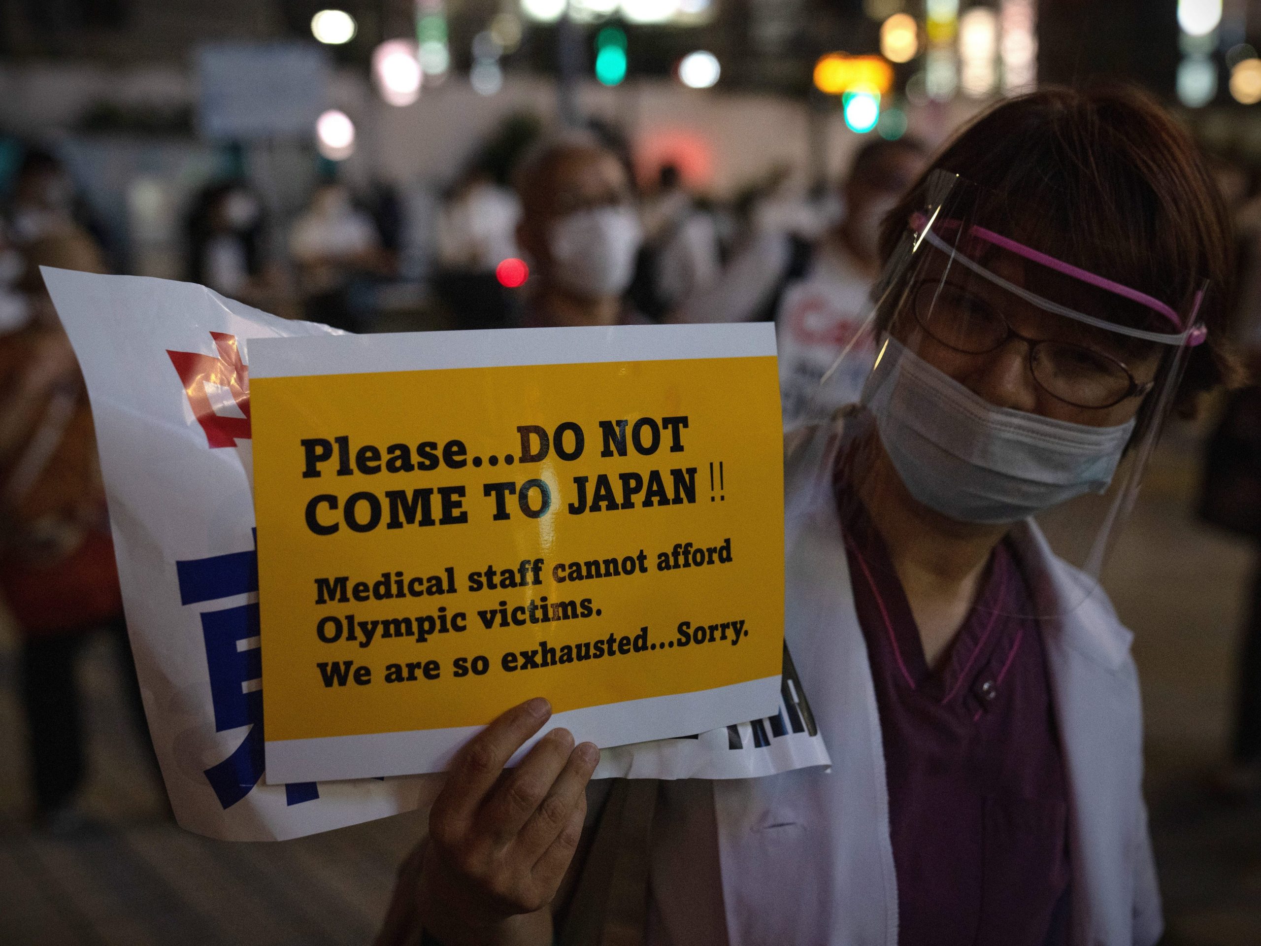 A doctor holds up a poster asking people not to come to Japan for the Olympics during a protest against the Olympic Games on June 23, 2021 in Tokyo, Japan. Protests have continued to take place in the run up to the Olympics amid concern over the safety of holding the Games during the global coronavirus pandemic.