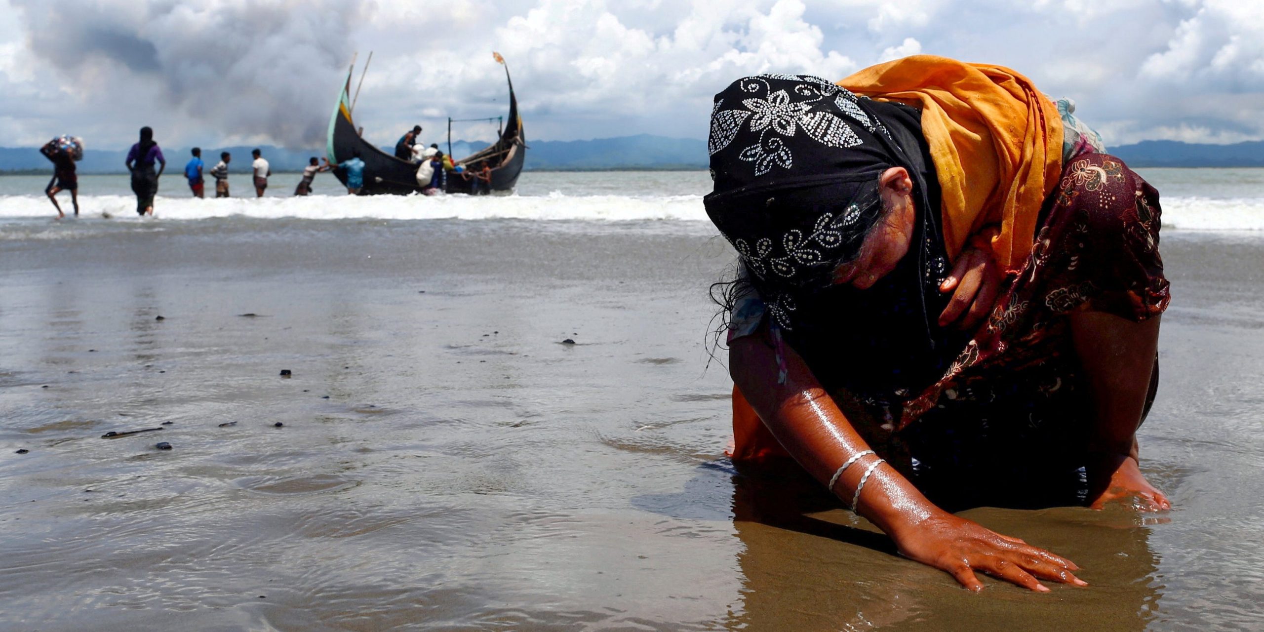 An exhausted Rohingya refugee woman touches the shore after crossing the Bangladesh-Myanmar border by boat through the Bay of Bengal, in Shah Porir Dwip, Bangladesh September 11, 2017.