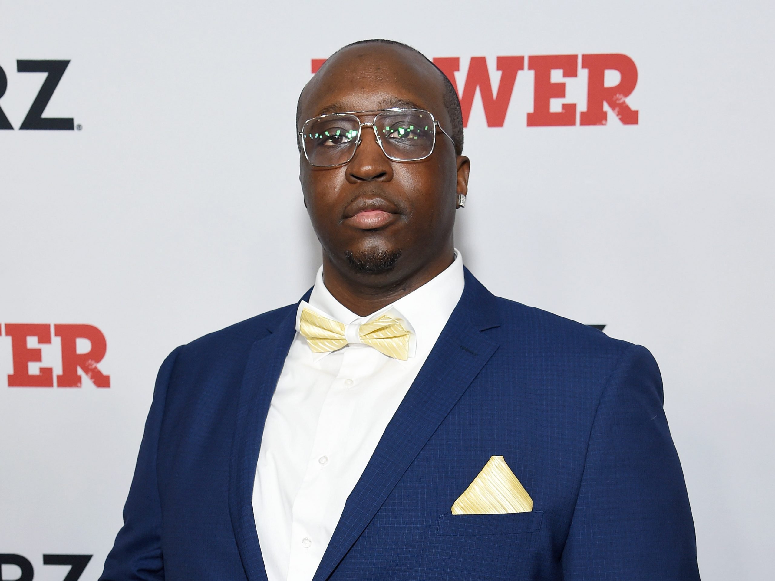 Isaiah Stokes wears a blue suit and yellow bow tie at the premiere of "Power" season six.