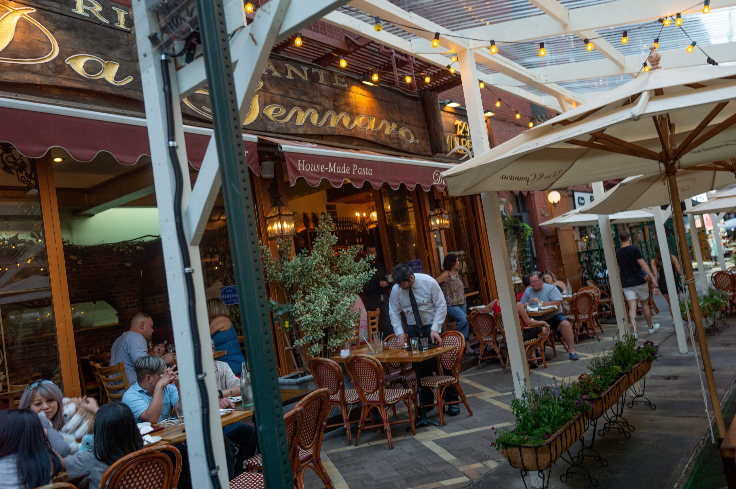 A view from the street of diners seated at sidewalk tables outside a restaurant.