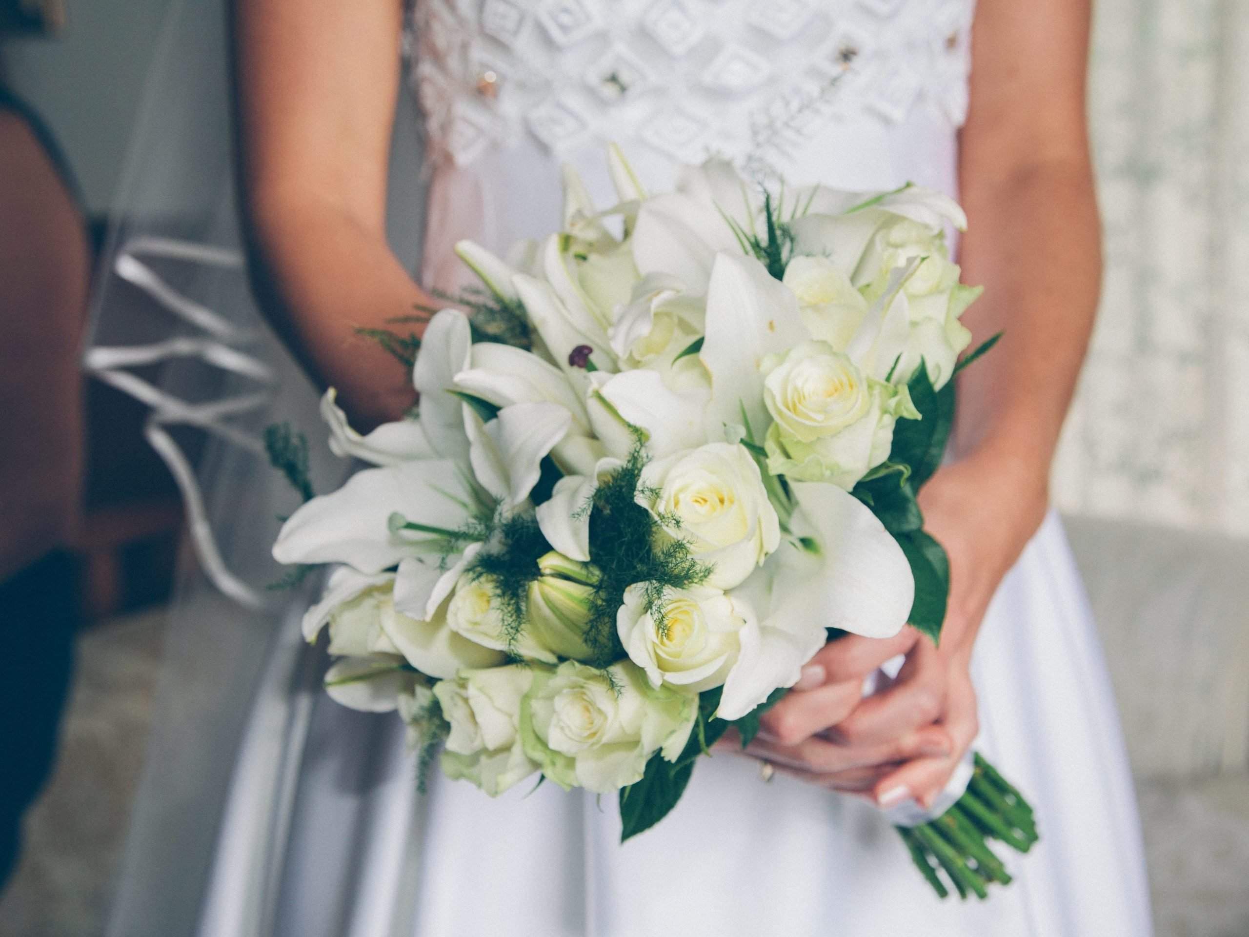 A bride wearing a white dress holds a flower bouquet