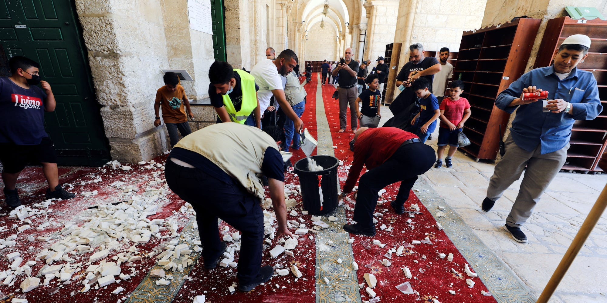 People clear the debris after brief clashes erupted between Israeli police and Palestinians at al-Aqsa Mosque over visits by Jews on the Tisha B'Av fast day to the compound known to Muslims as Noble Sanctuary and to Jews as Temple Mount, in Jerusalem's Old City, July 18, 2021.