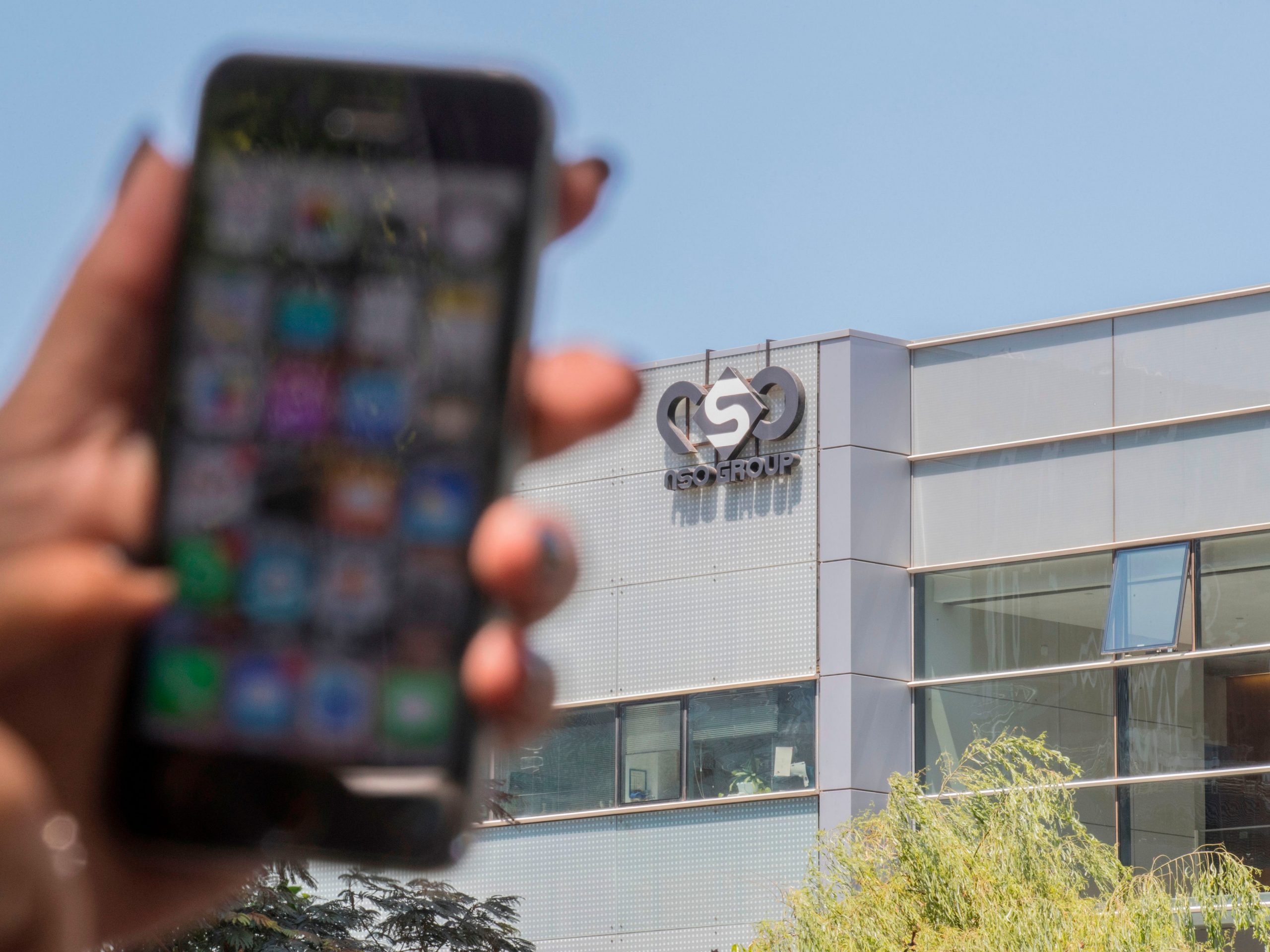 Woman holds phone outside NSO Group in Herzliya