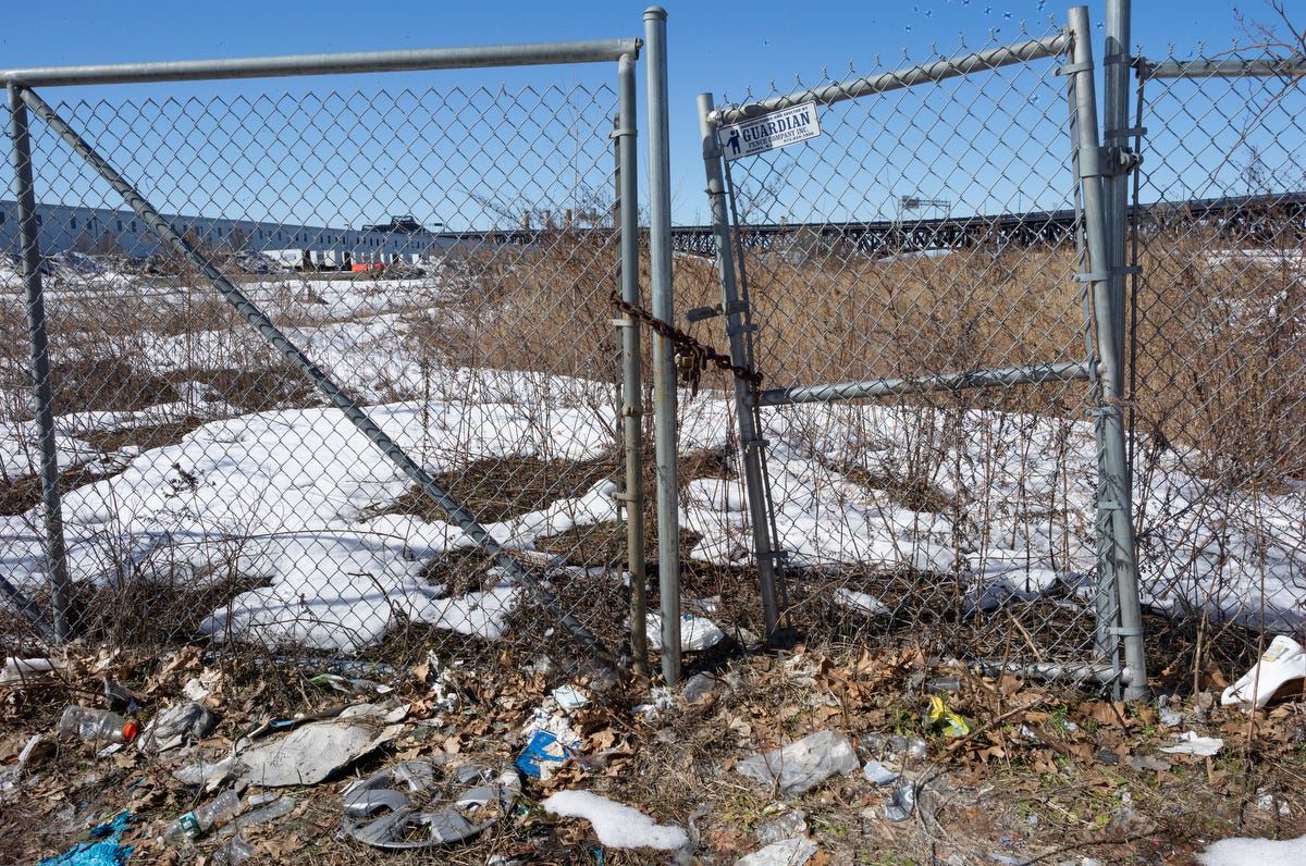 A partially open chainlink fence leads to a field.