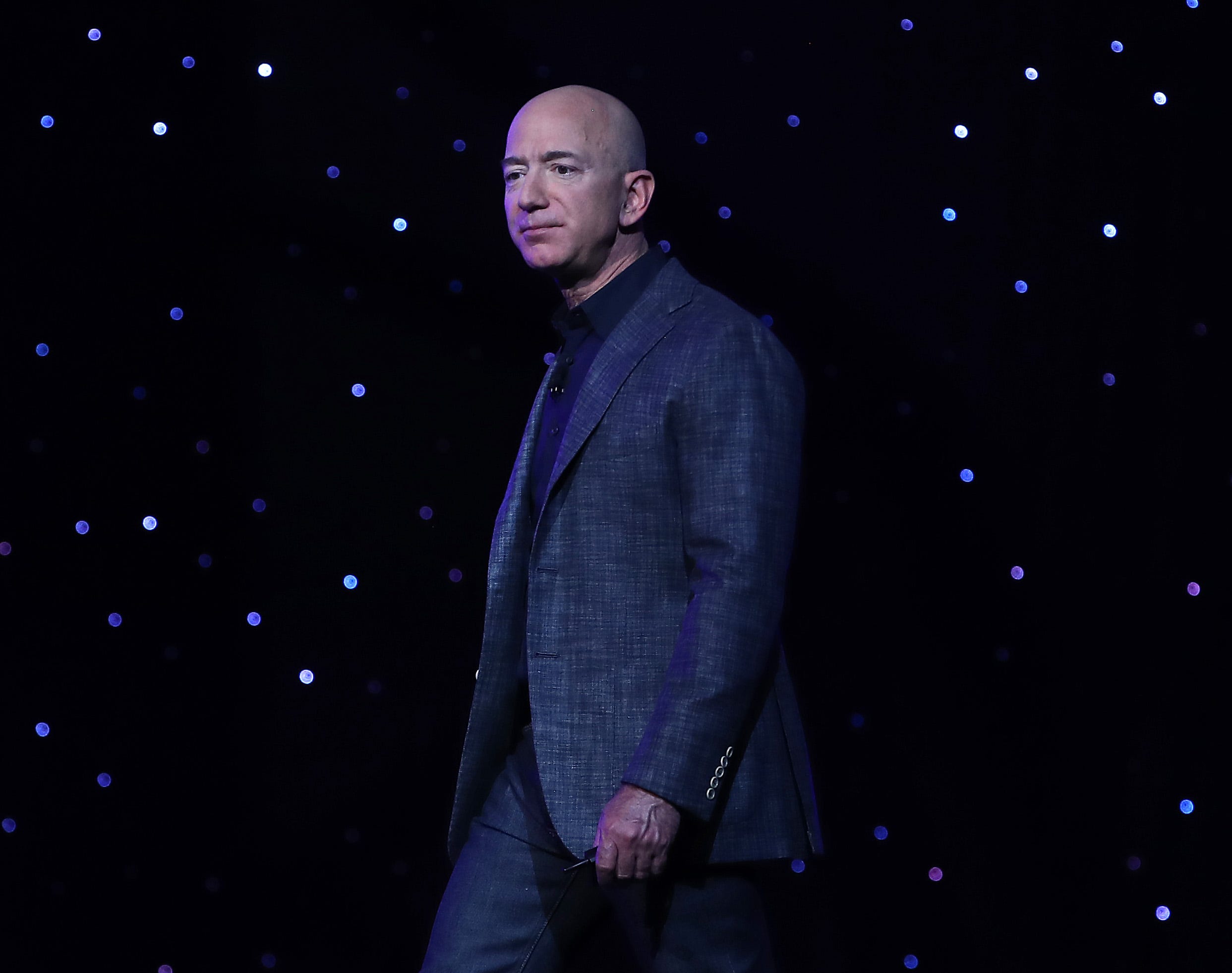 Jeff Bezos is seen in front of a background covered with stars.