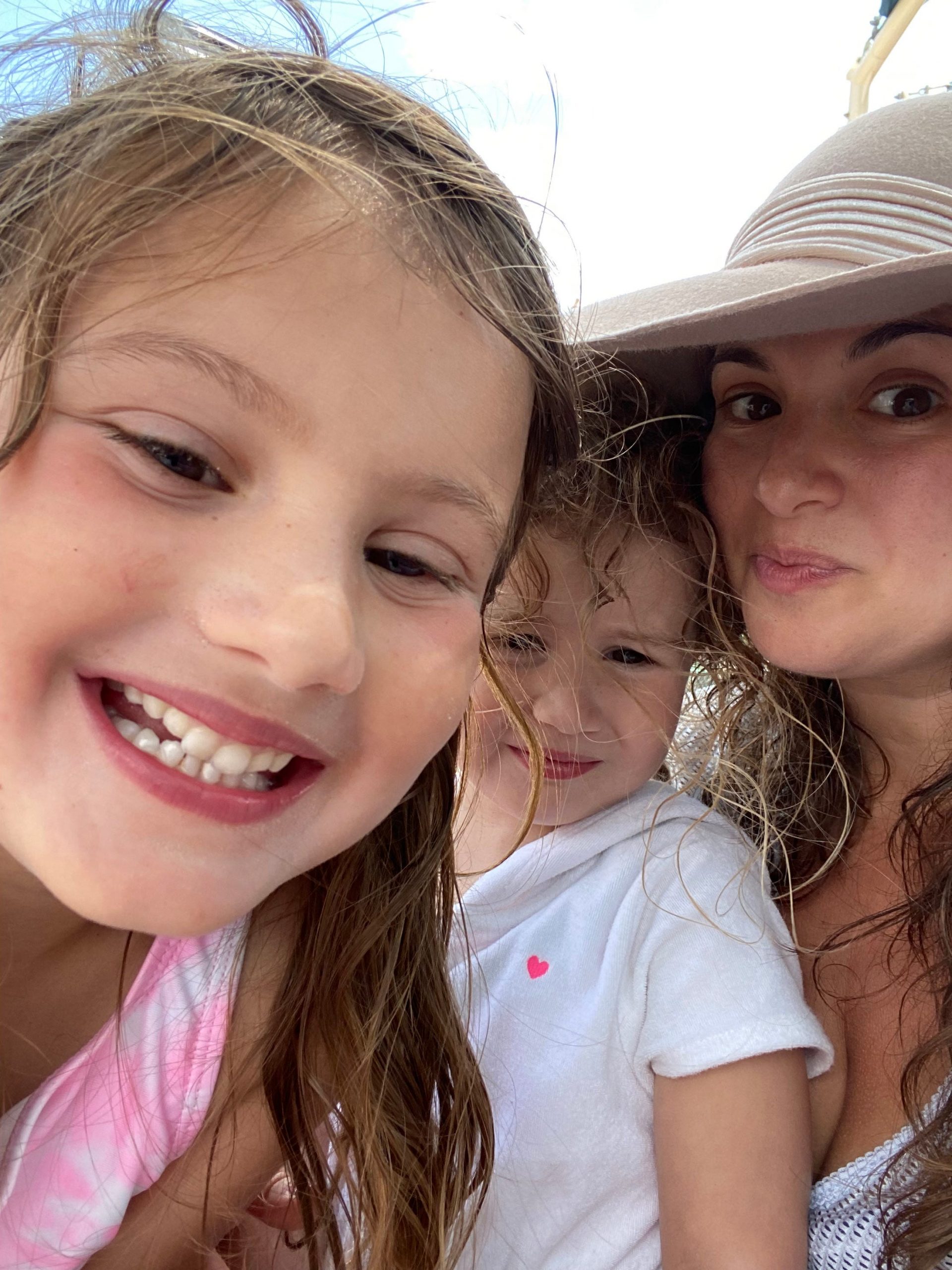 hilary young in a hat on the beach with her two daughters, 6 and 3.
