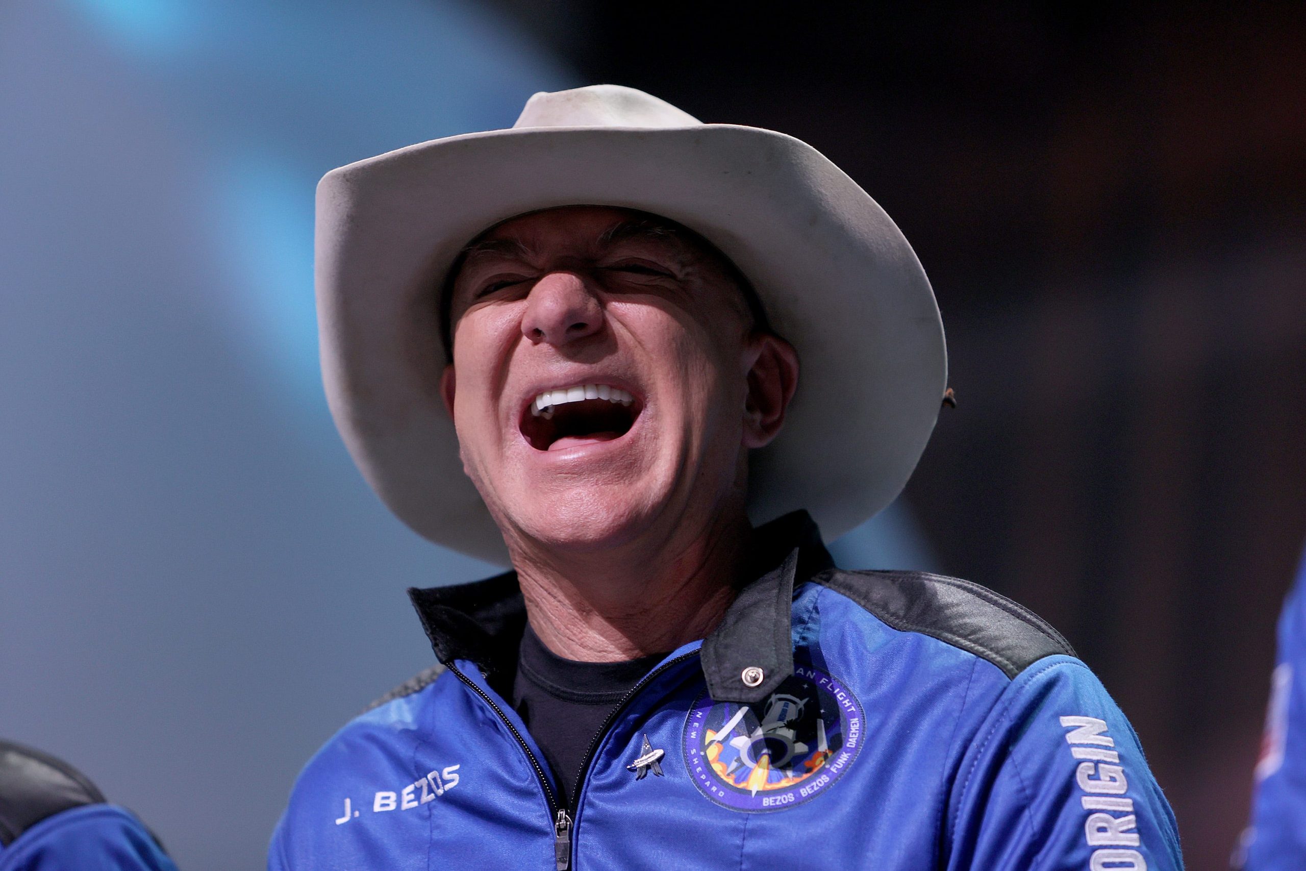 Jeff Bezos laughs wearing a cowboy hat