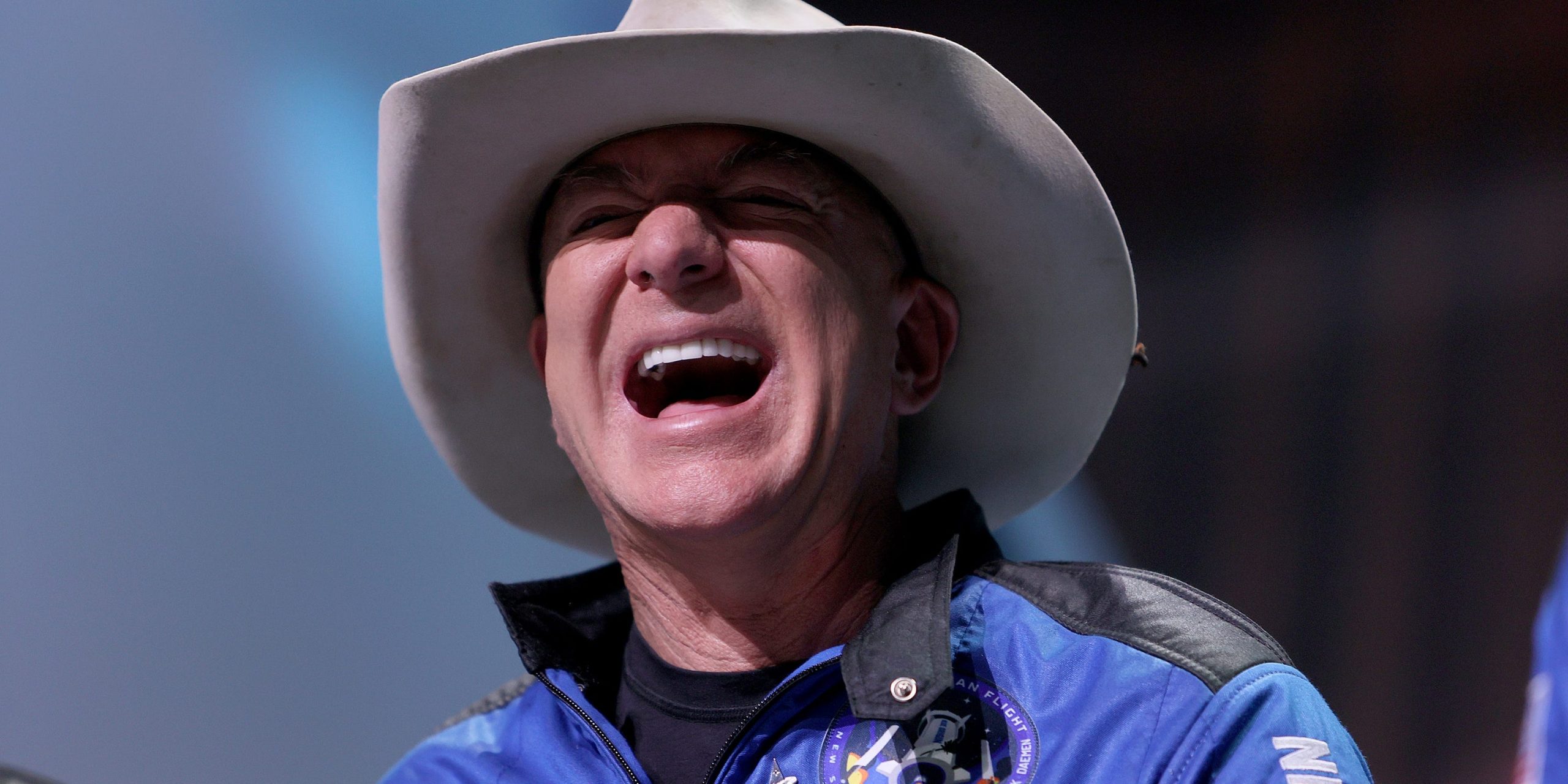 Jeff Bezos laughs wearing a cowboy hat