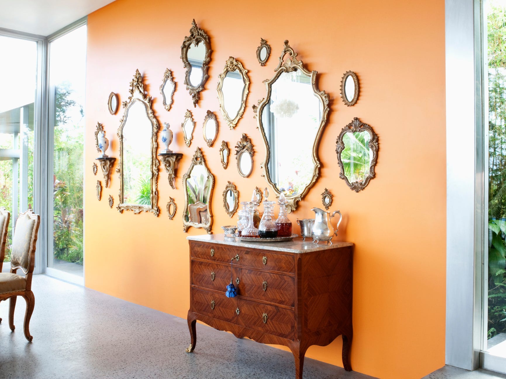 Several ornate gold mirrors all hung on an orange wall