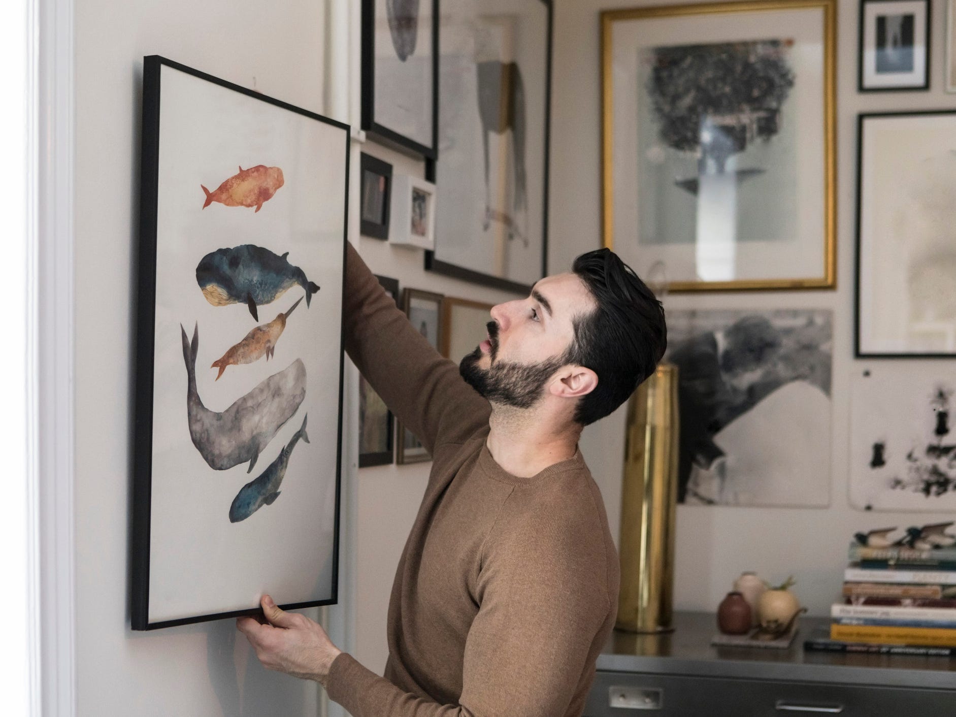 A man hanging art on his wall