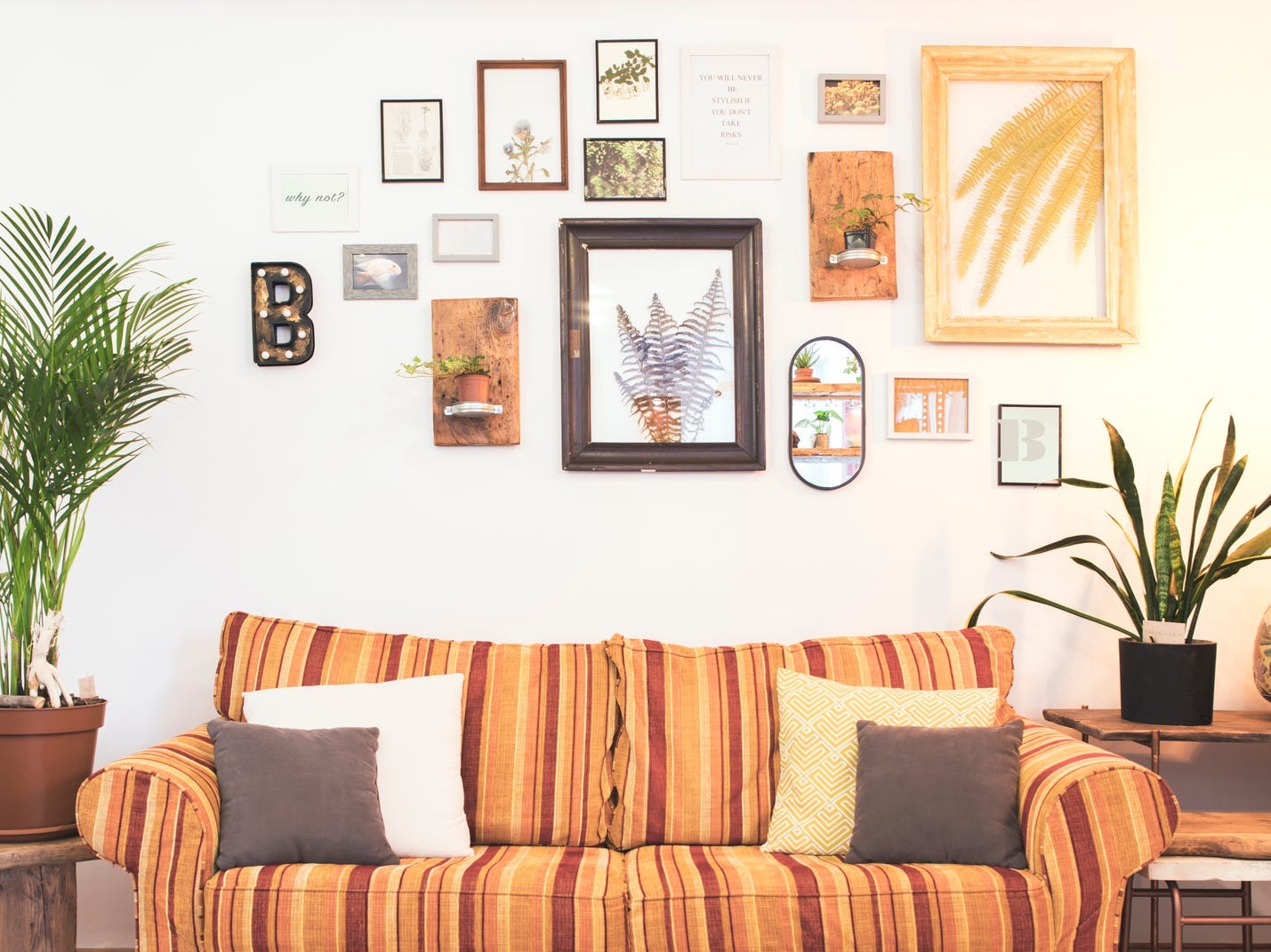 A living room with an orange striped couch and an eclectic collection of art arranged in a gallery wall