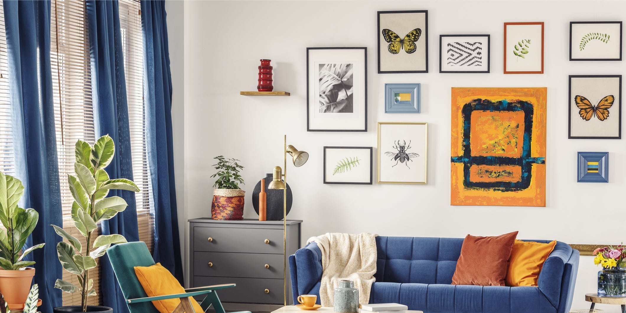 A brightly colored living room with a blue couch and several pieces of art arranged on the walls