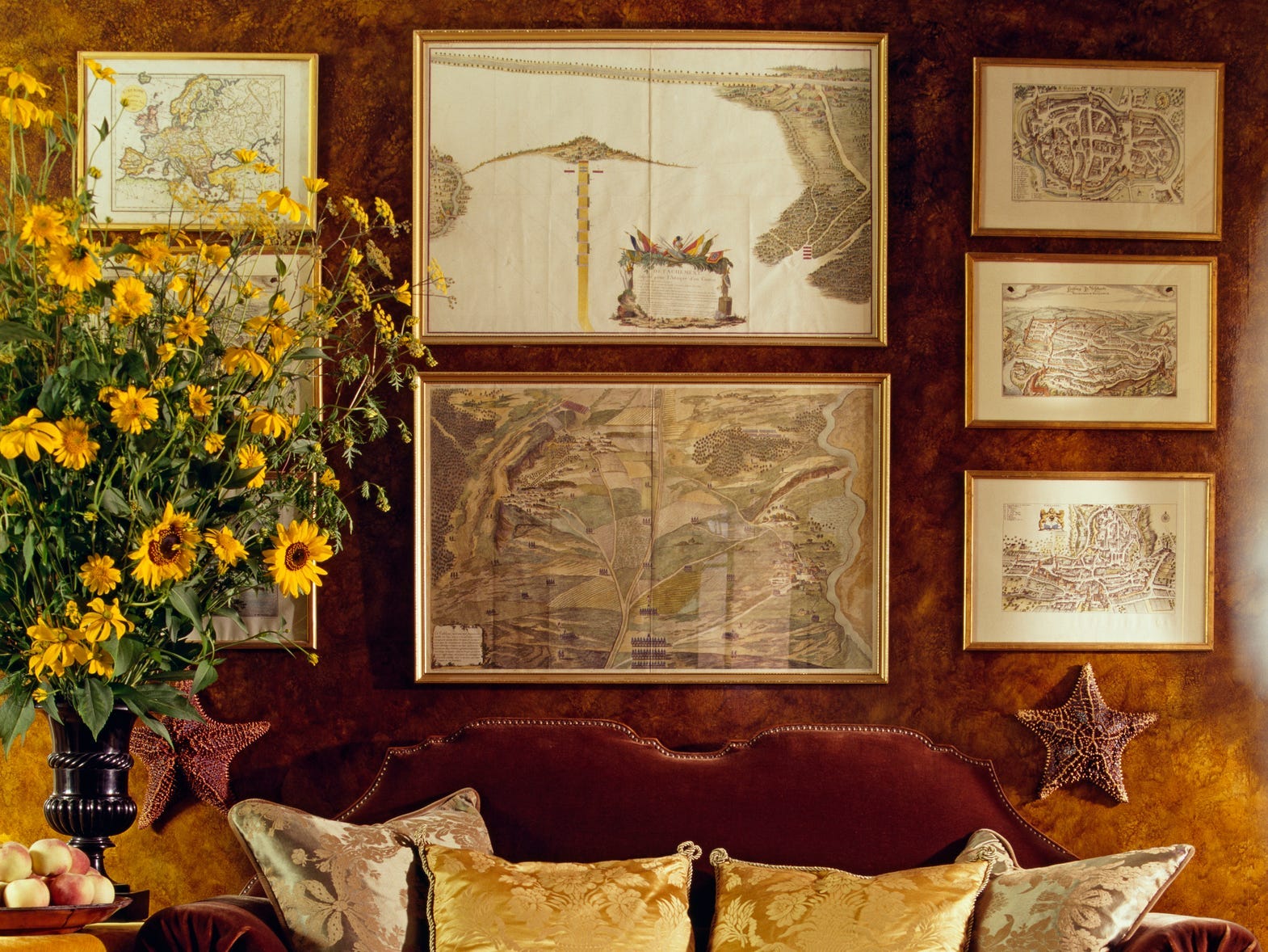 A red velvet sofa against a rich brown wall with symmetrical art hung on the walls above it