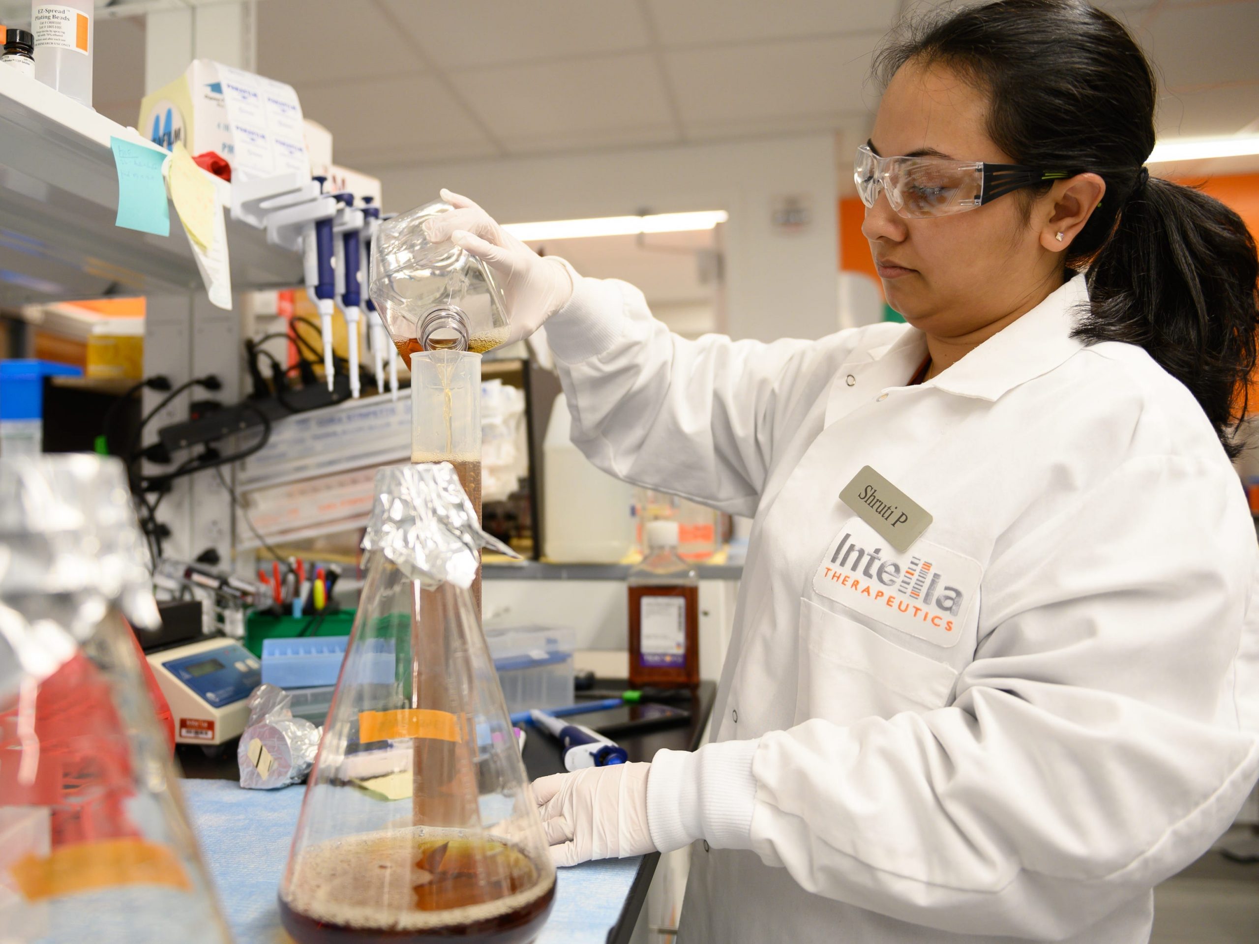 A scientist wearing a white coat and pouring liquid into a beaker at Intellia Therapeutics' lab in Cambridge, Massachusetts.