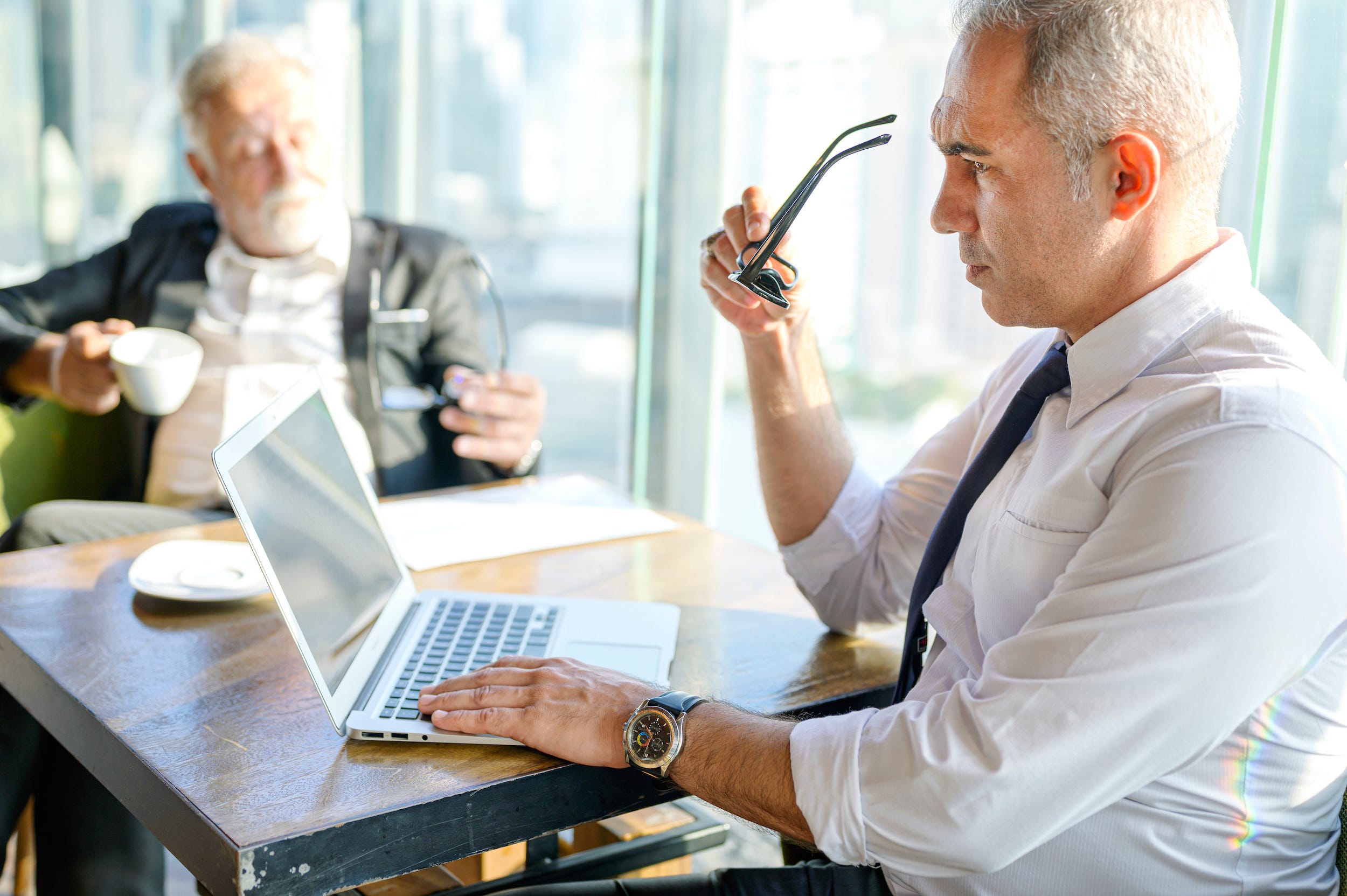 Business man using laptop computer with coworker in office