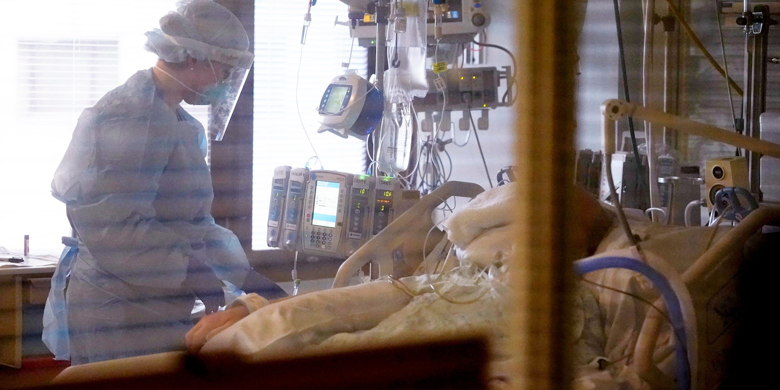 nurse treats a patient in hospital COVID intensive care unit