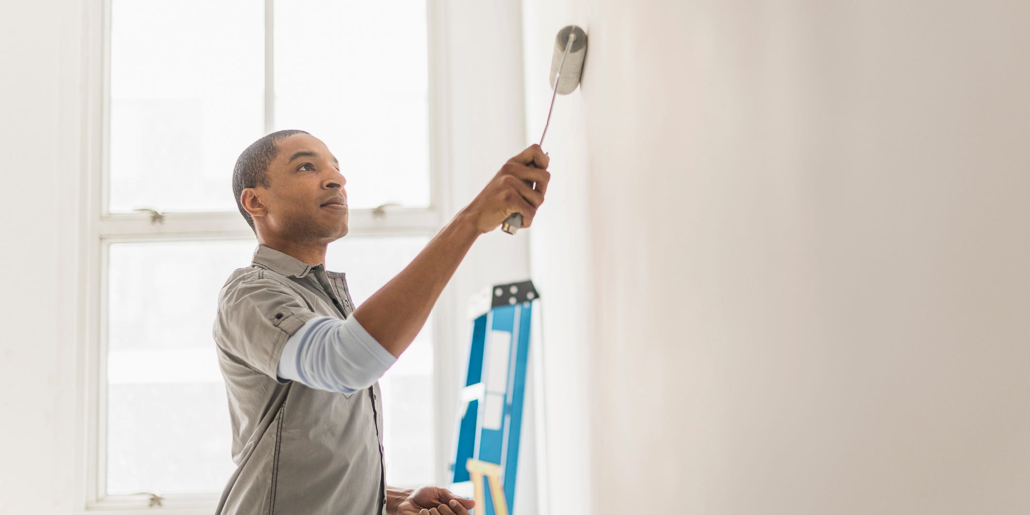 A person painting a wall with a paint roller