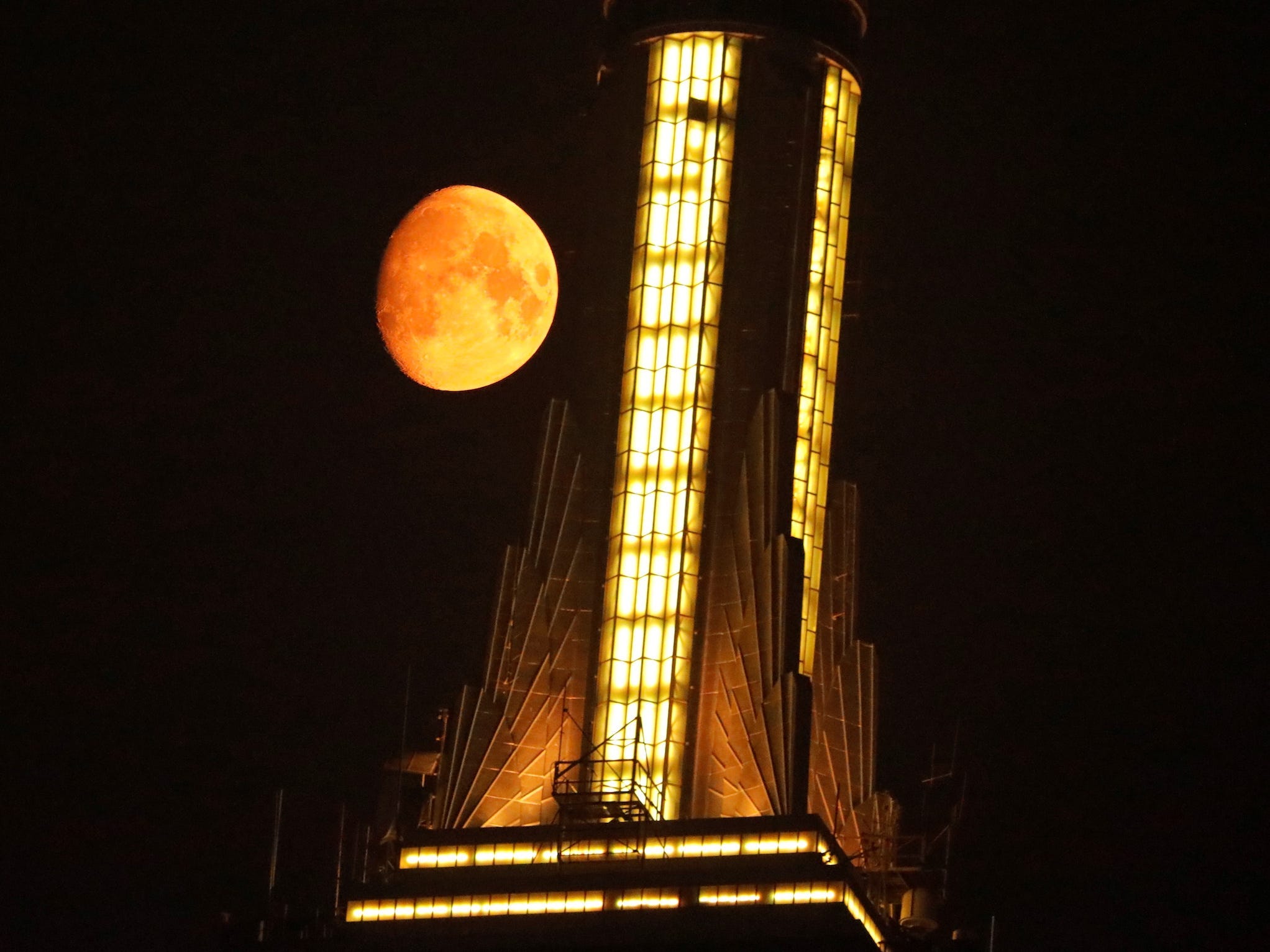 orange moon next to empire state building spire