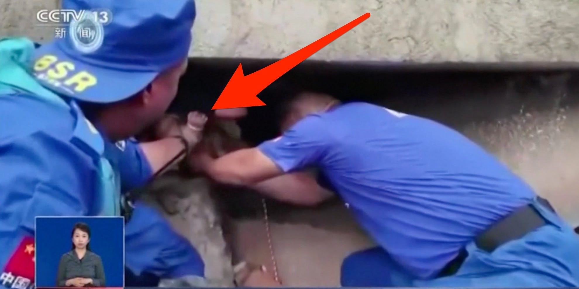 An arrow pointing to a baby's hand as she is pulled from rubble by rescuers.
