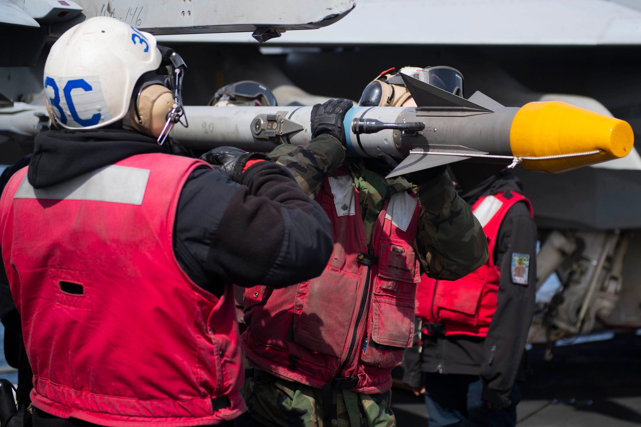 Sailors load missile on fighter jet on USS Theodore Roosevelt aircraft carrier