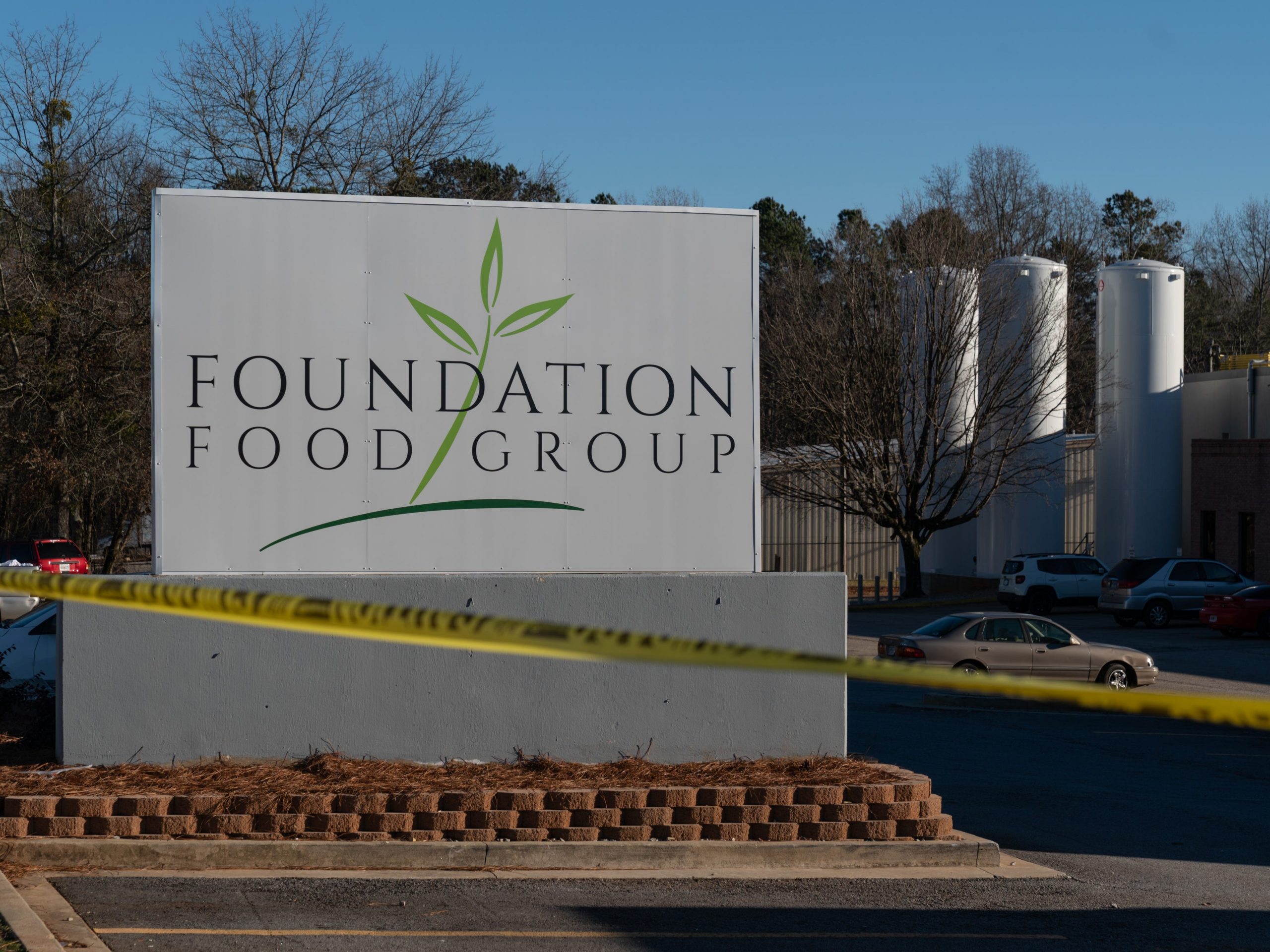 A photos of the Foundation Food Group sign with police tape in front of it.