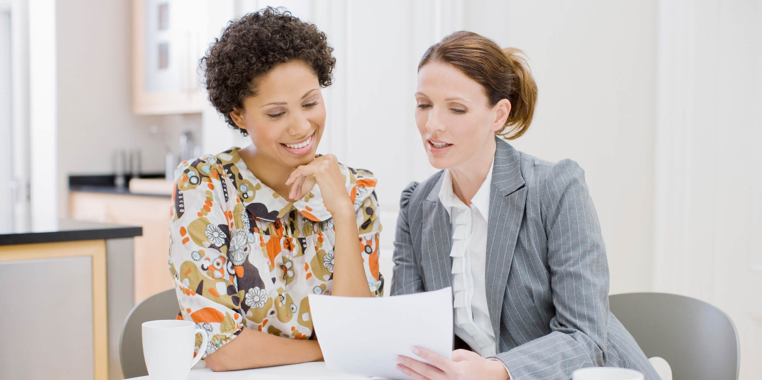 Businesswoman reviewing paperwork with woman.