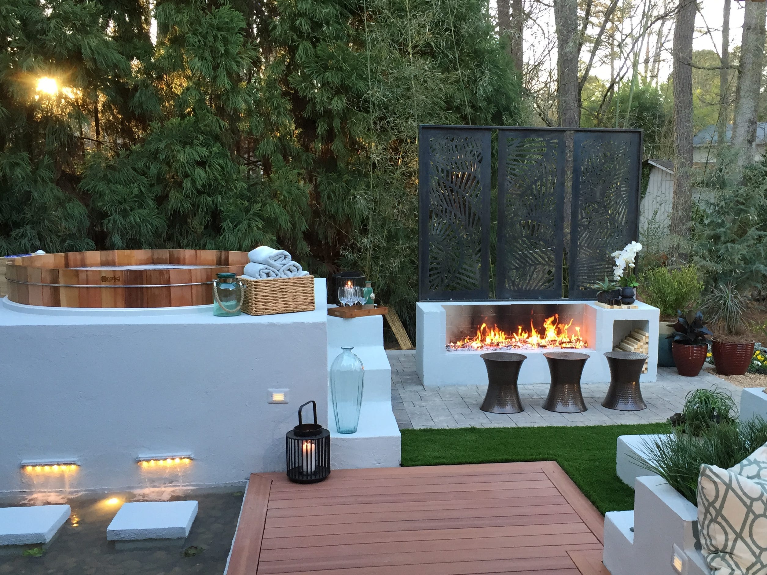 A luxury backyard with a hot tub, fire pit, and couch seating area