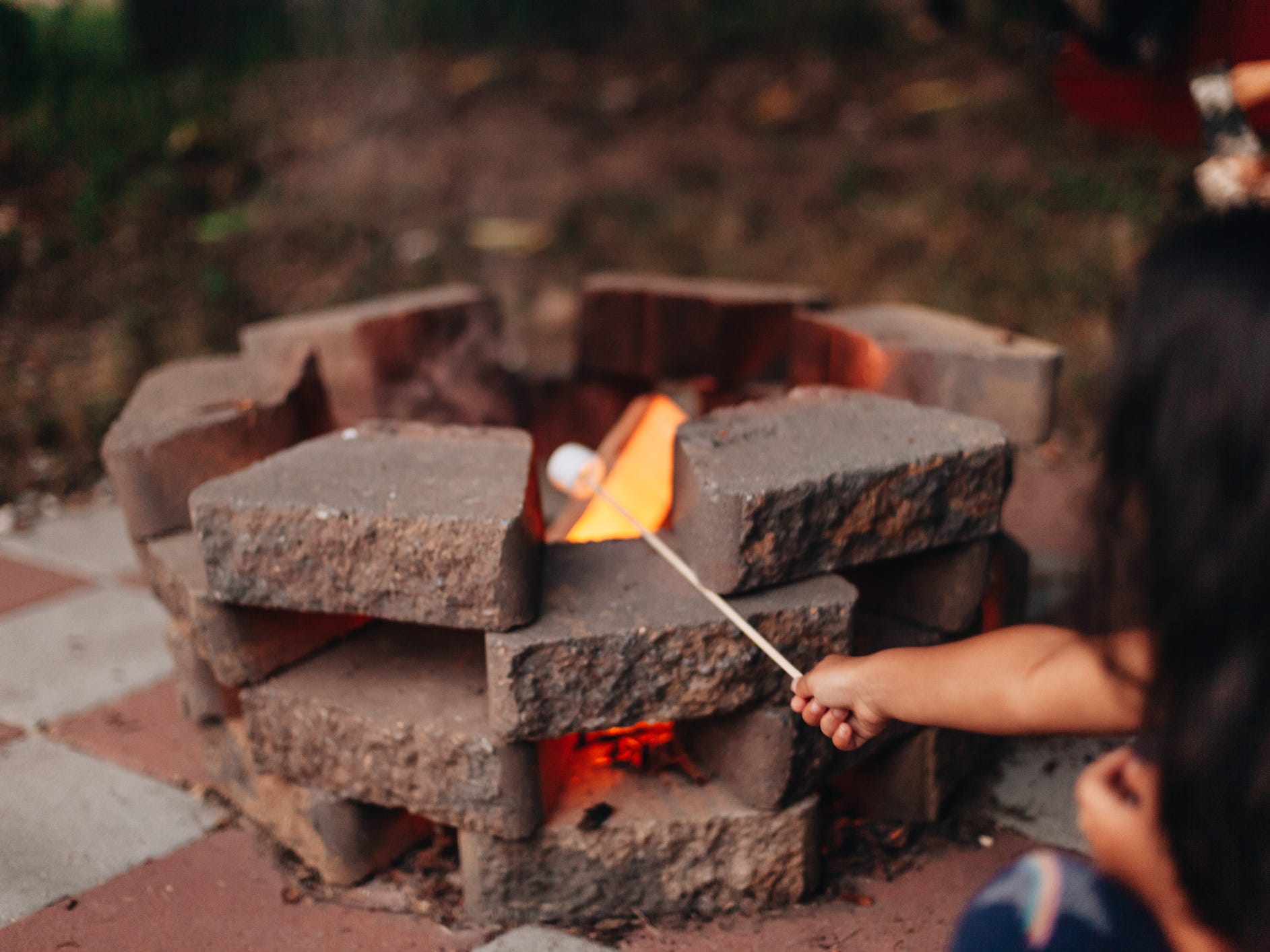 A child roasting a marshmallow over a simple stone fire pit
