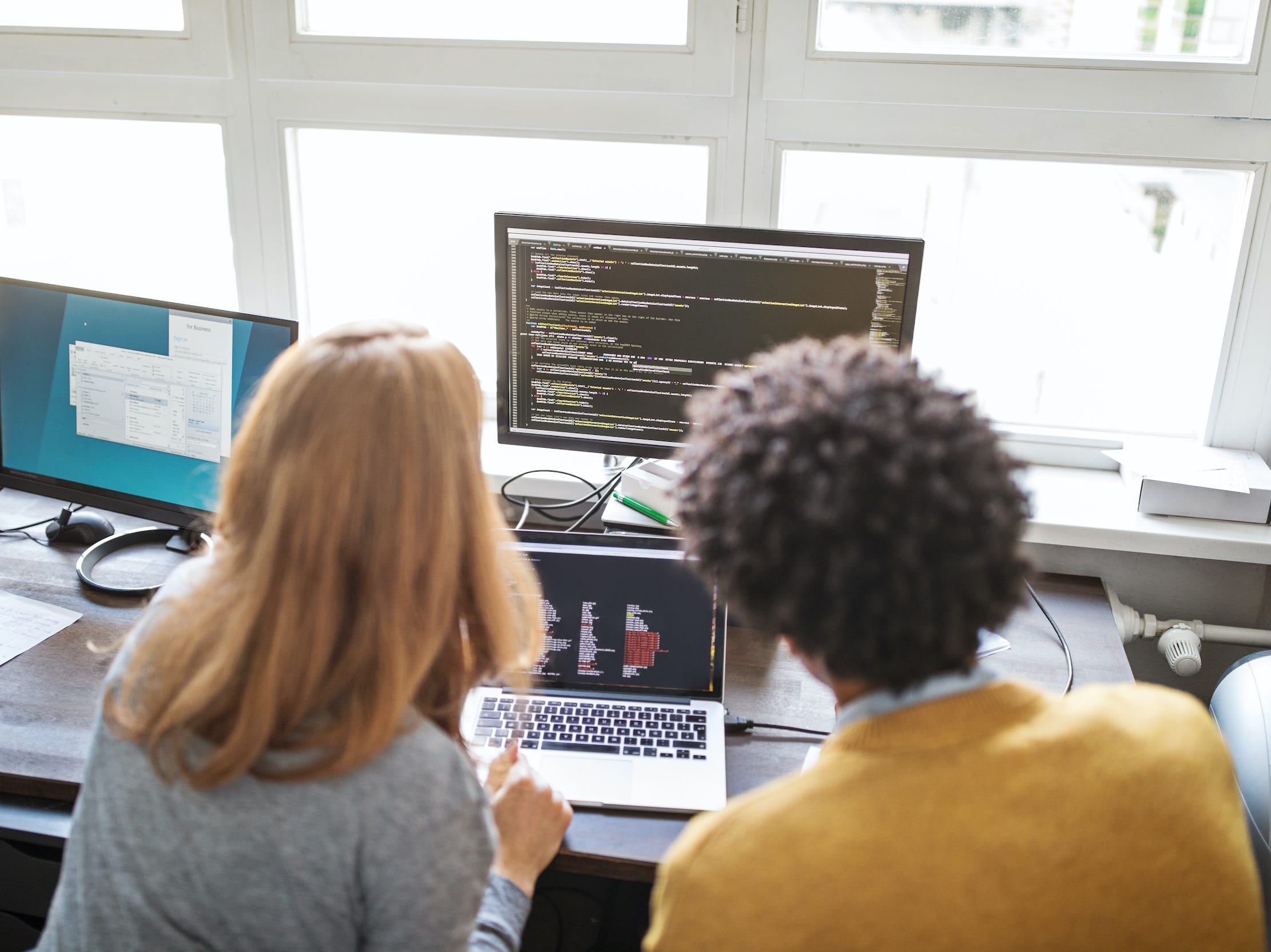 Two coworkers coding on a shared computer together